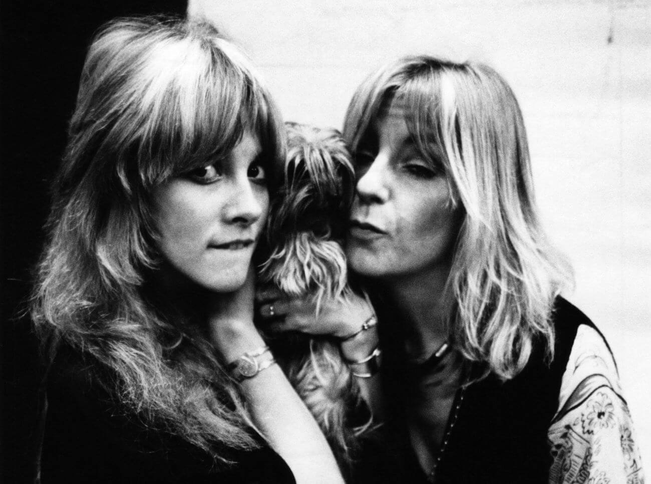A black and white picture of Stevie Nicks and Christine McVie posing with a dog.