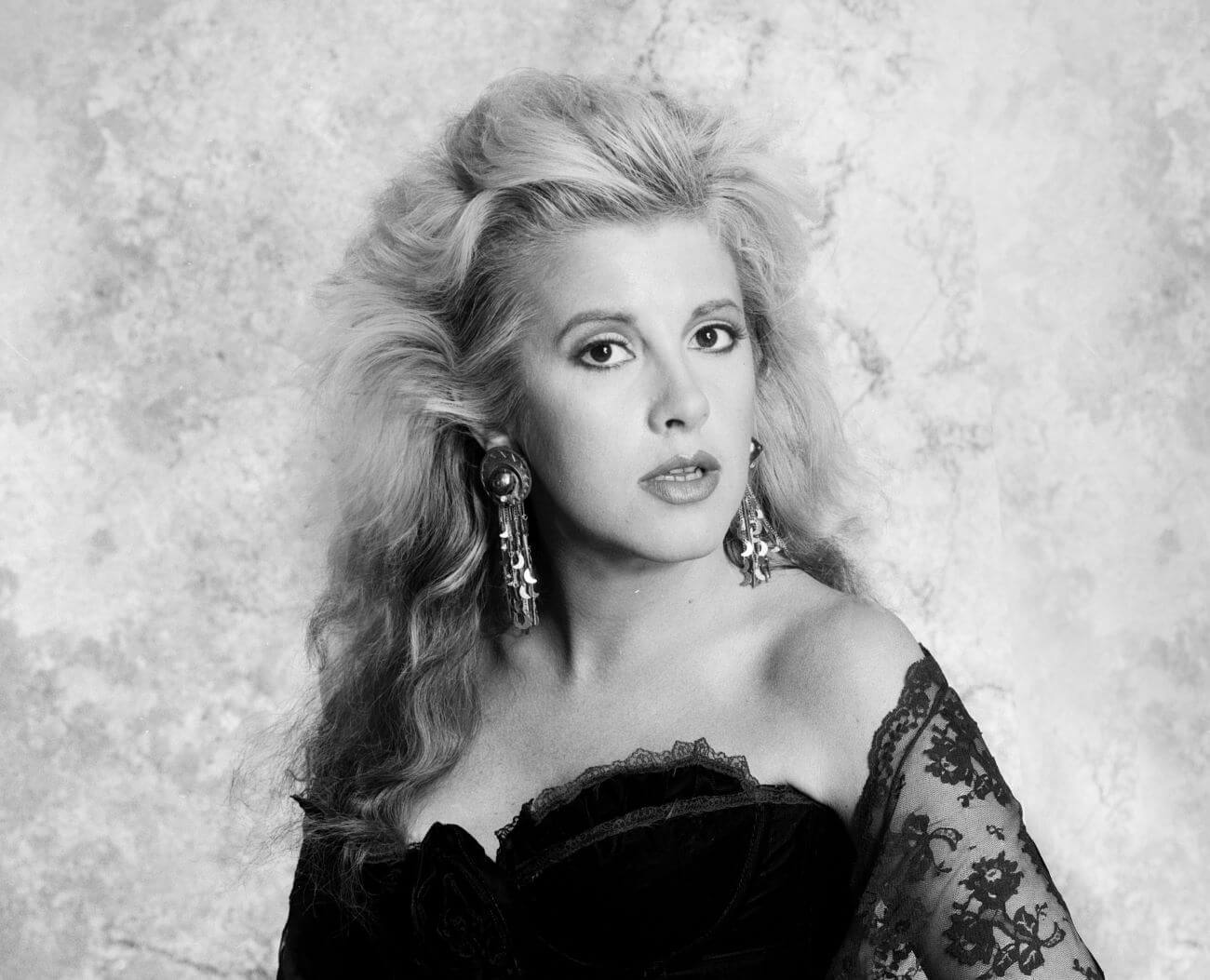 A black and white picture of Stevie Nicks wearing a lace shawl and moon earrings.