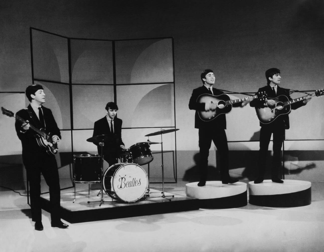 A black and white picture of Paul McCartney, Ringo Starr, John Lennon, and George Harrison of The Beatles performing together.