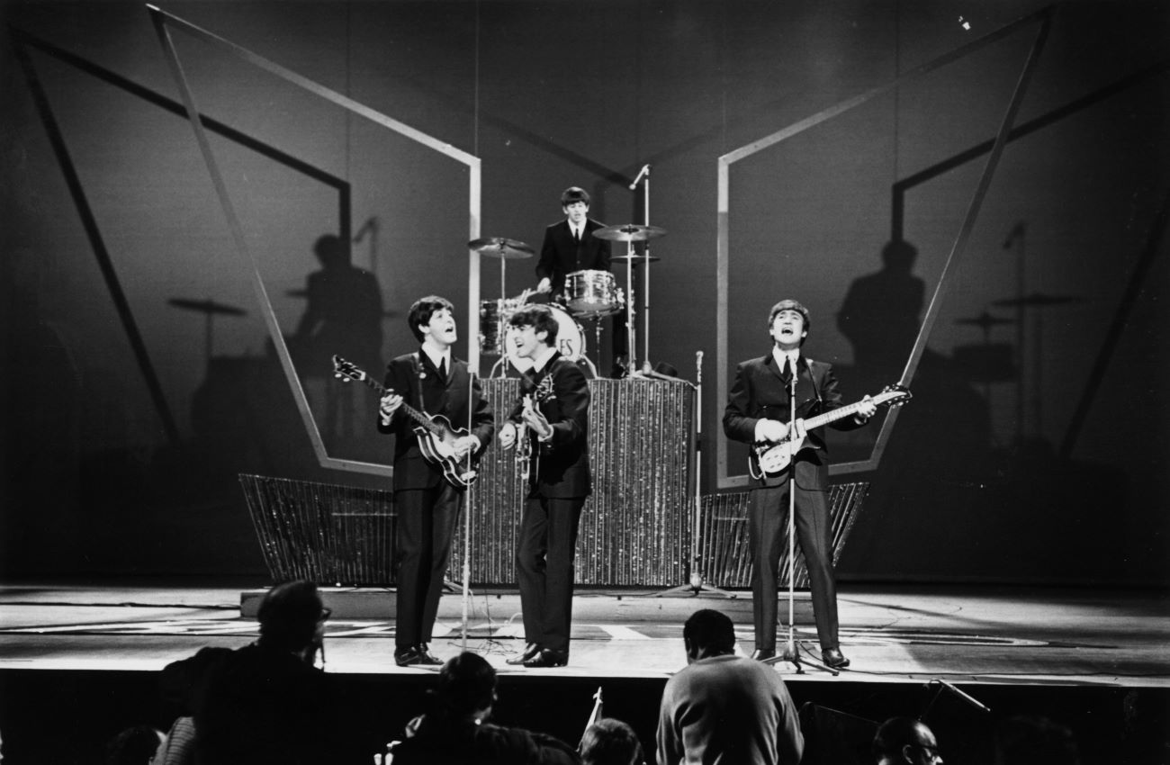 A black and white picture of The Beatles performing live on a stage.