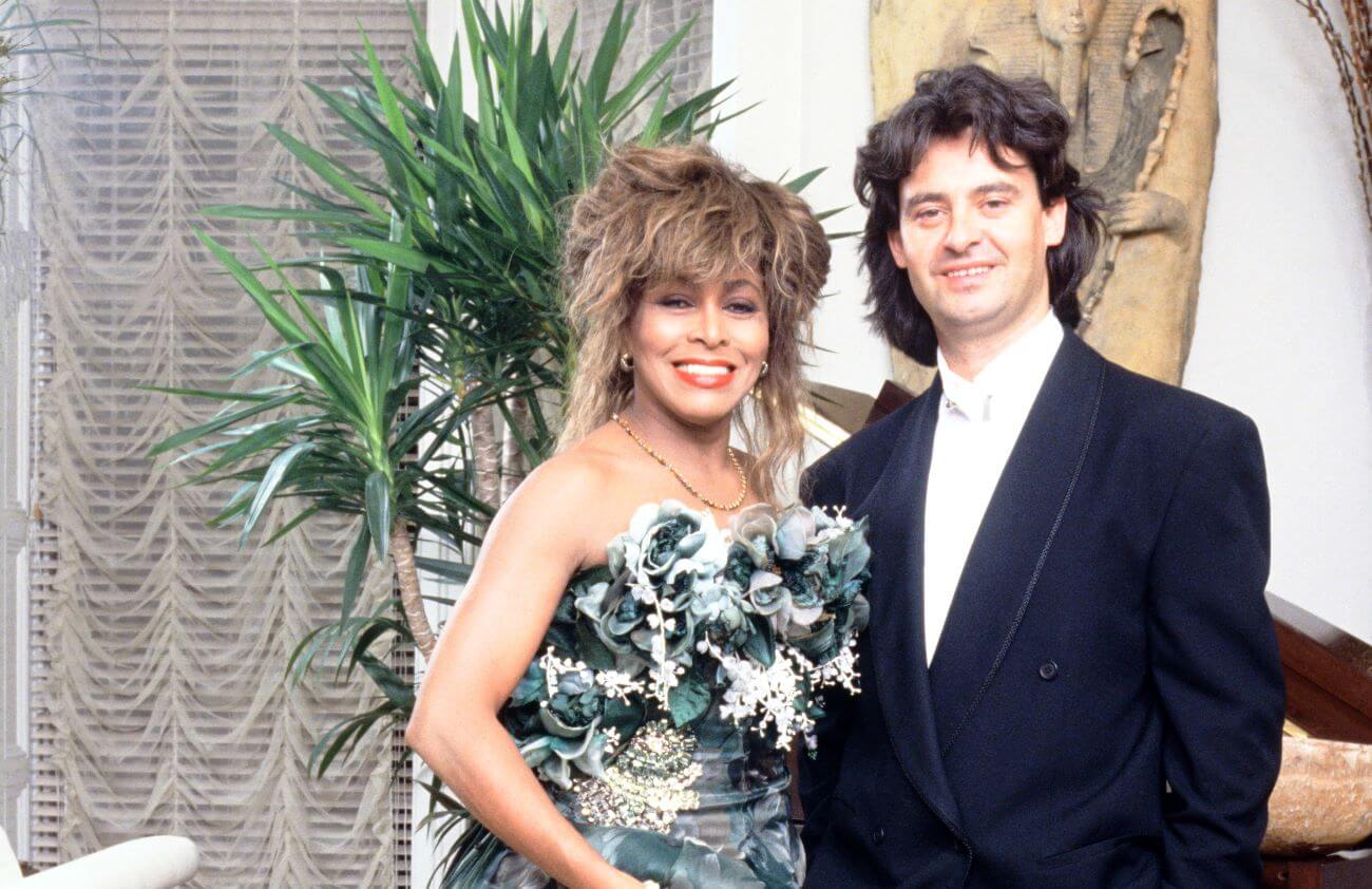 Tina Turner wears a flowery dress and stands with Erwin Bach, who wears a suit.