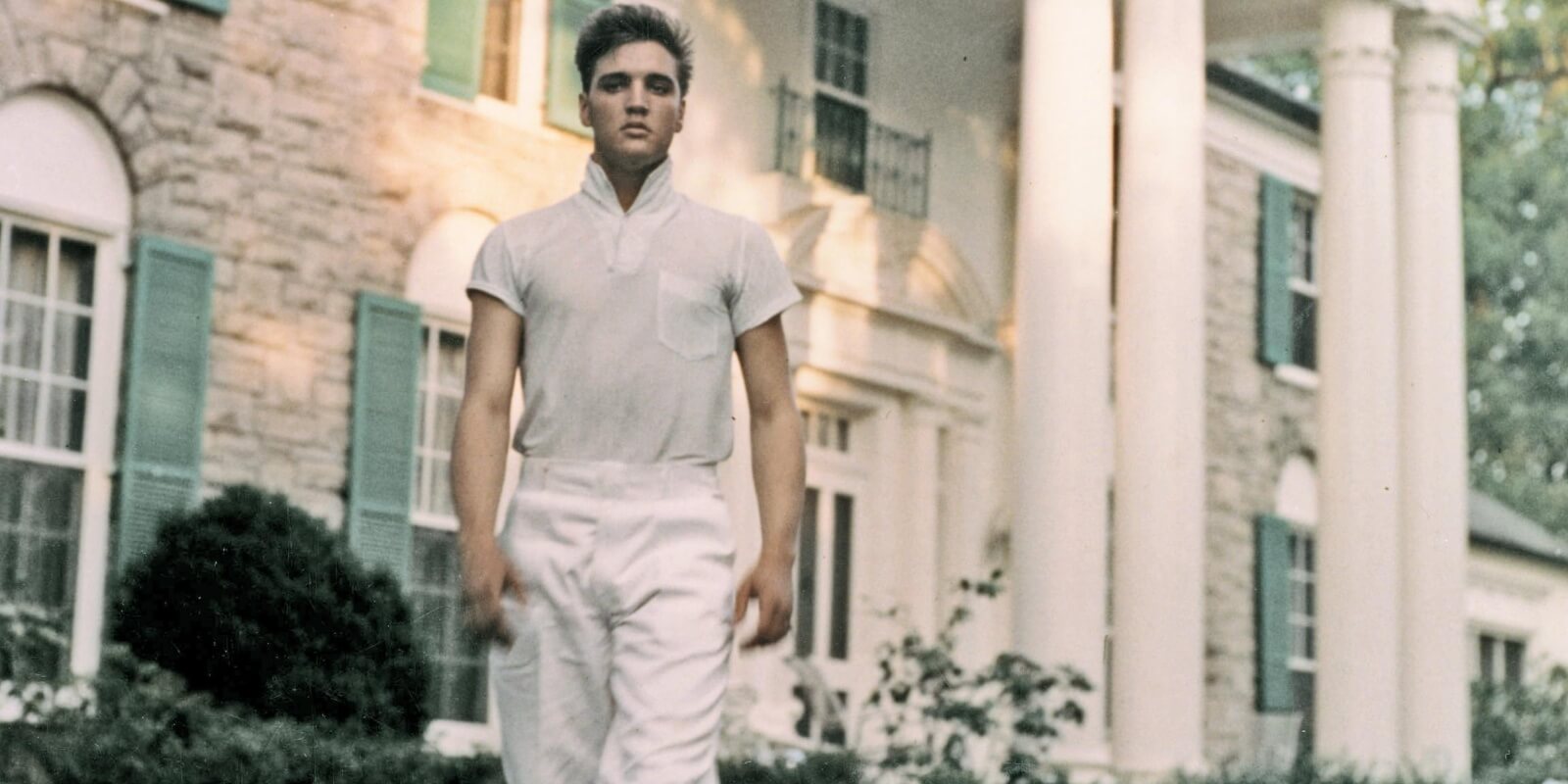 Elvis Presley poses in front of his Graceland home in 1957.