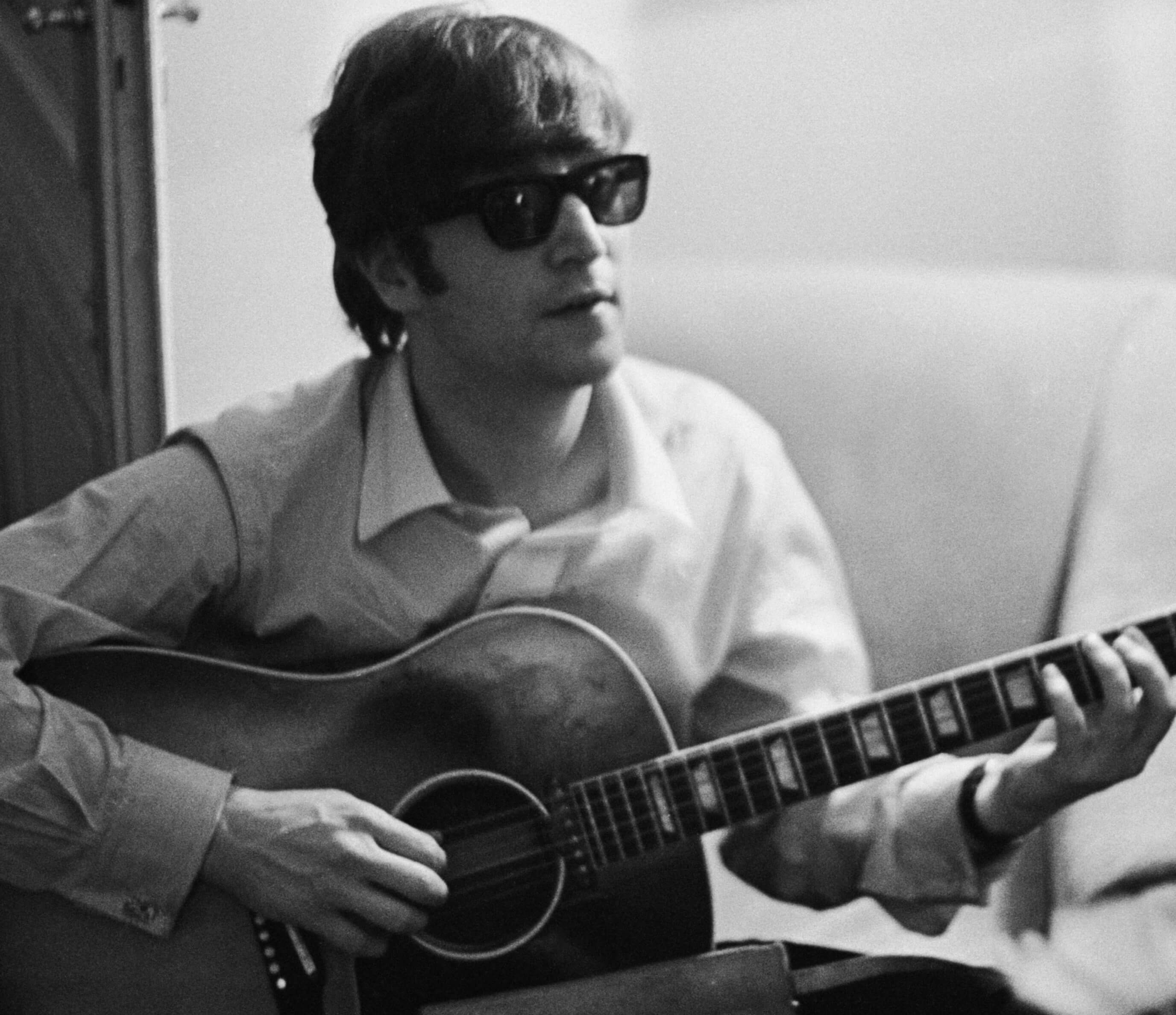 John Lennon playing a song on a guitar