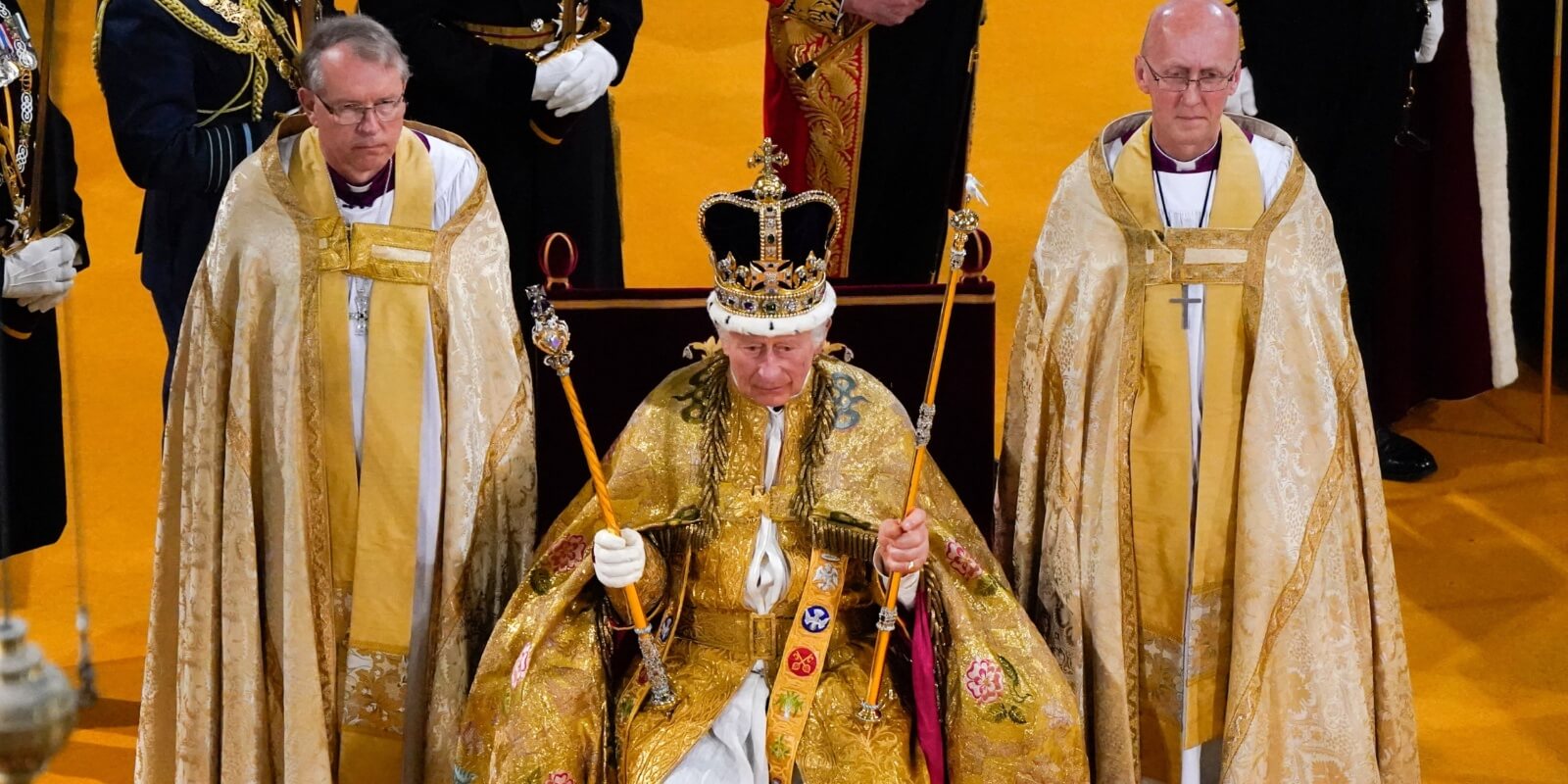 King Charles is seated in the coronation chair inside of Westminster Abbey during his coronation.