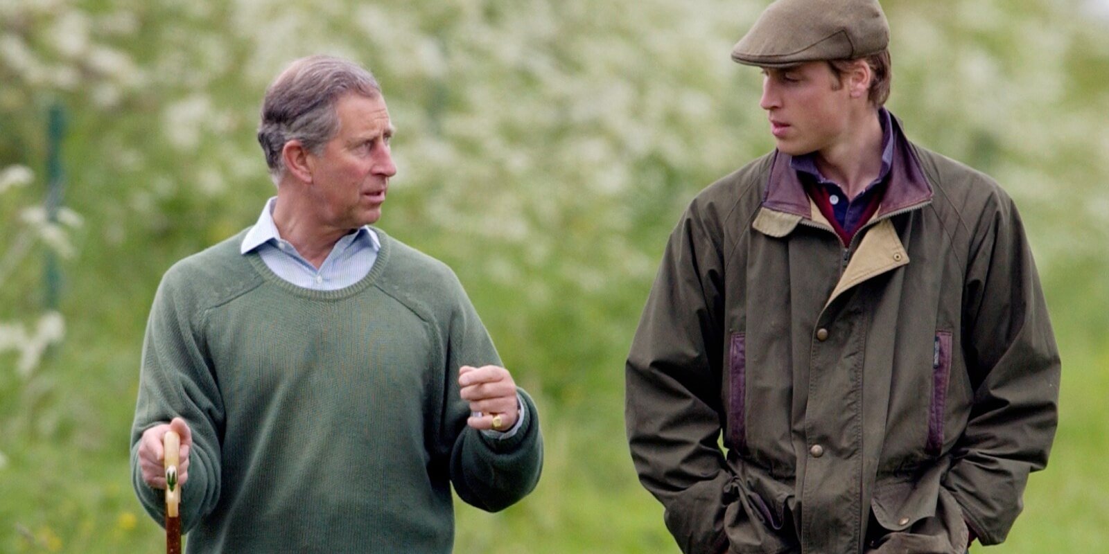 King Charles and Prince William walk together on the grounds of a royal residence.