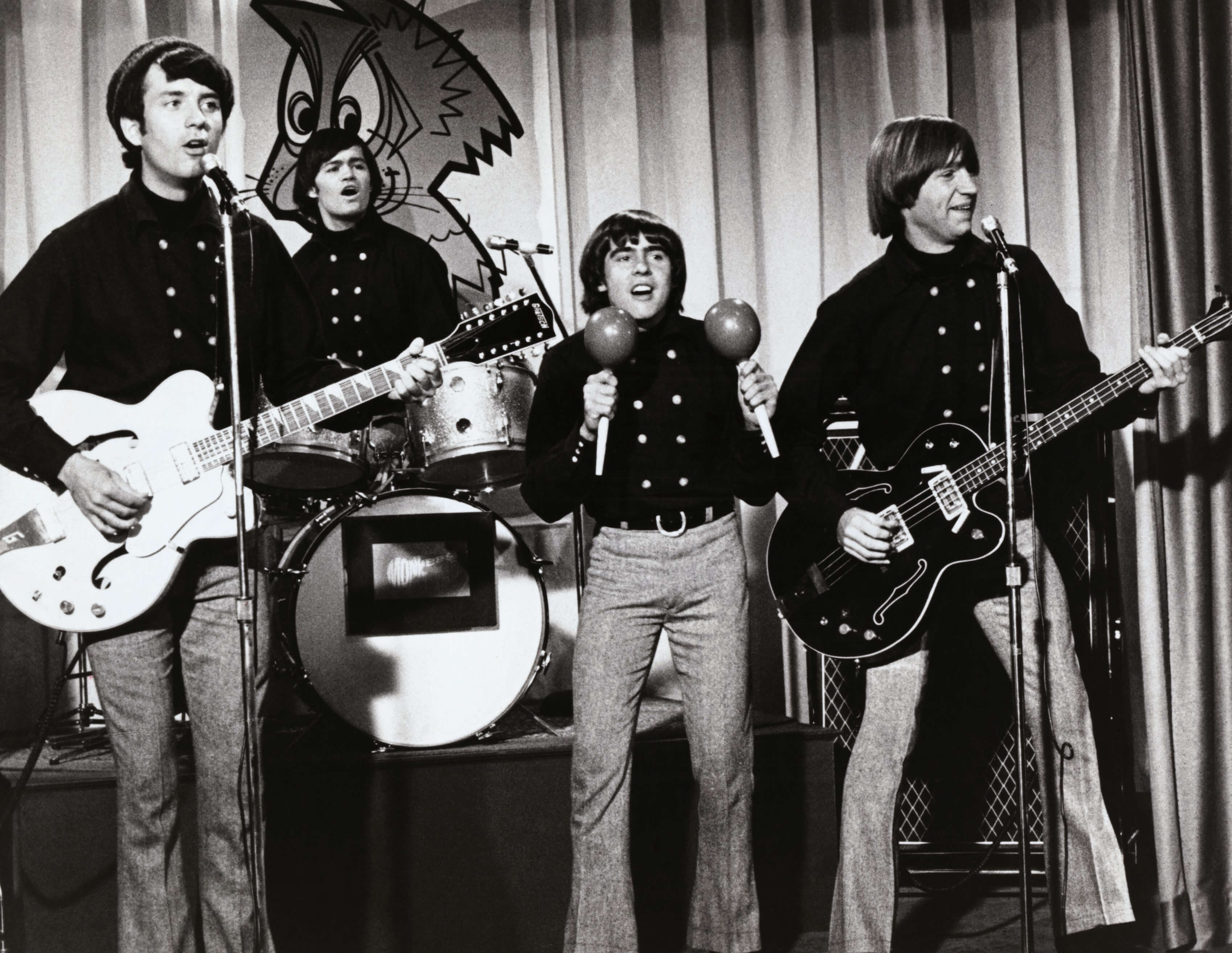 The Monkees' Mike Nesmith, Micky Dolenz, Davy Jones, and Peter Tork in front of a curtain