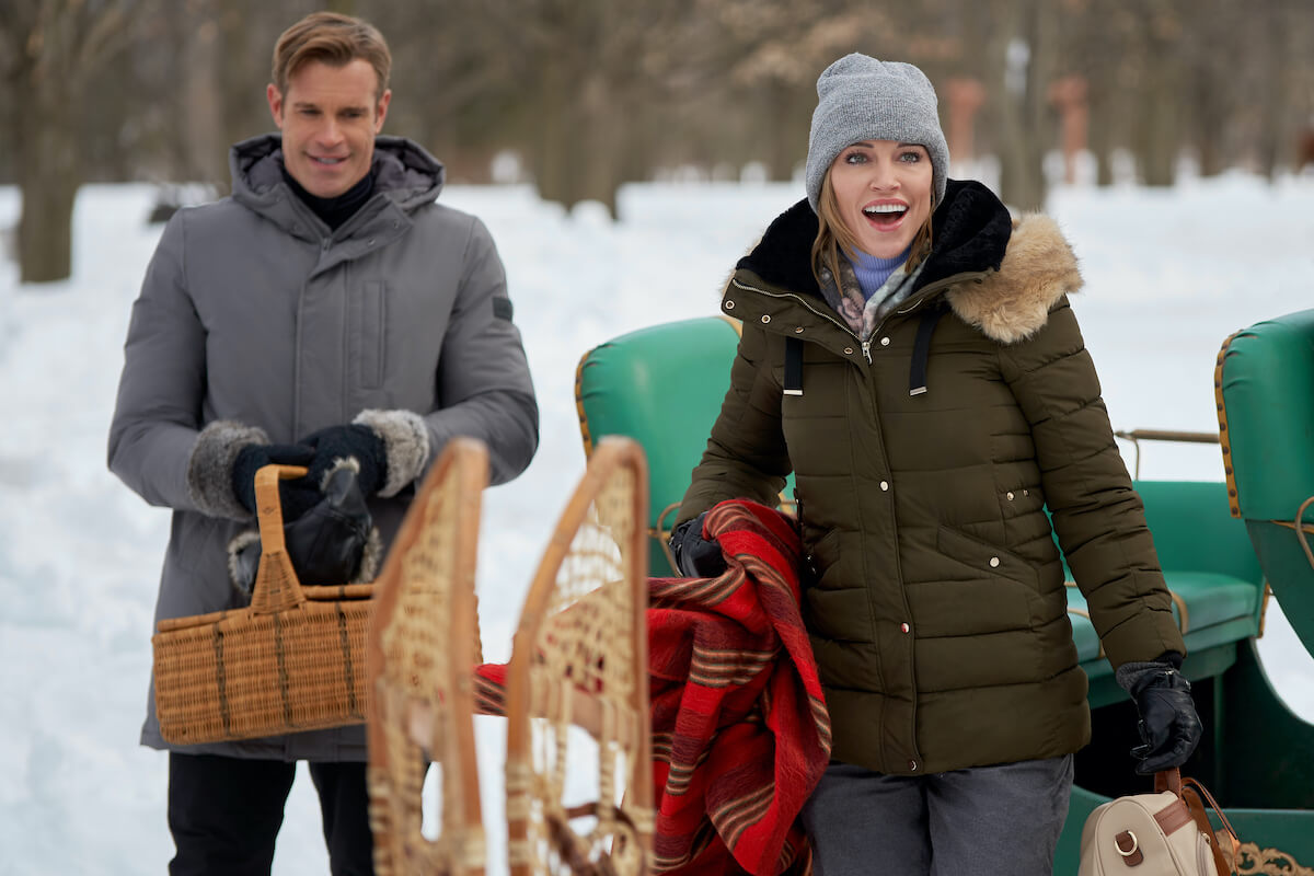 Stephen Huszar and Katie Cassidy with sleds in Hallmark's Christmas in July movie 'A Royal Christmas Crush'