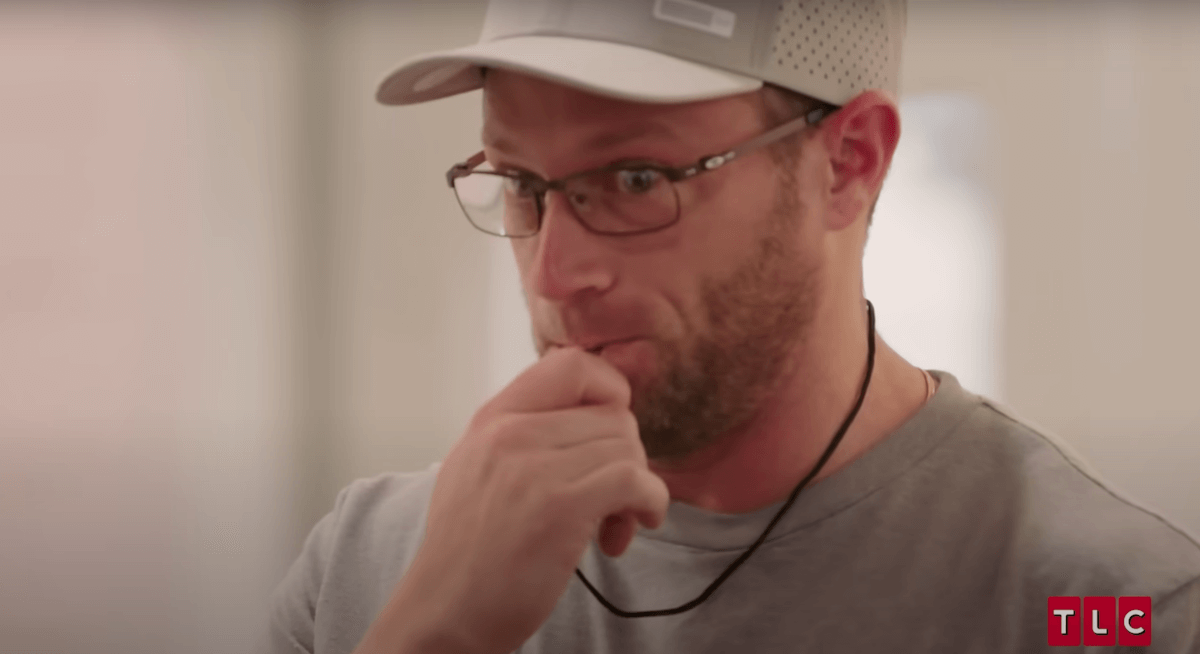 Adam Busby of TLC's 'OutDaughtered' wearing a baseball cap and blowign a whistle