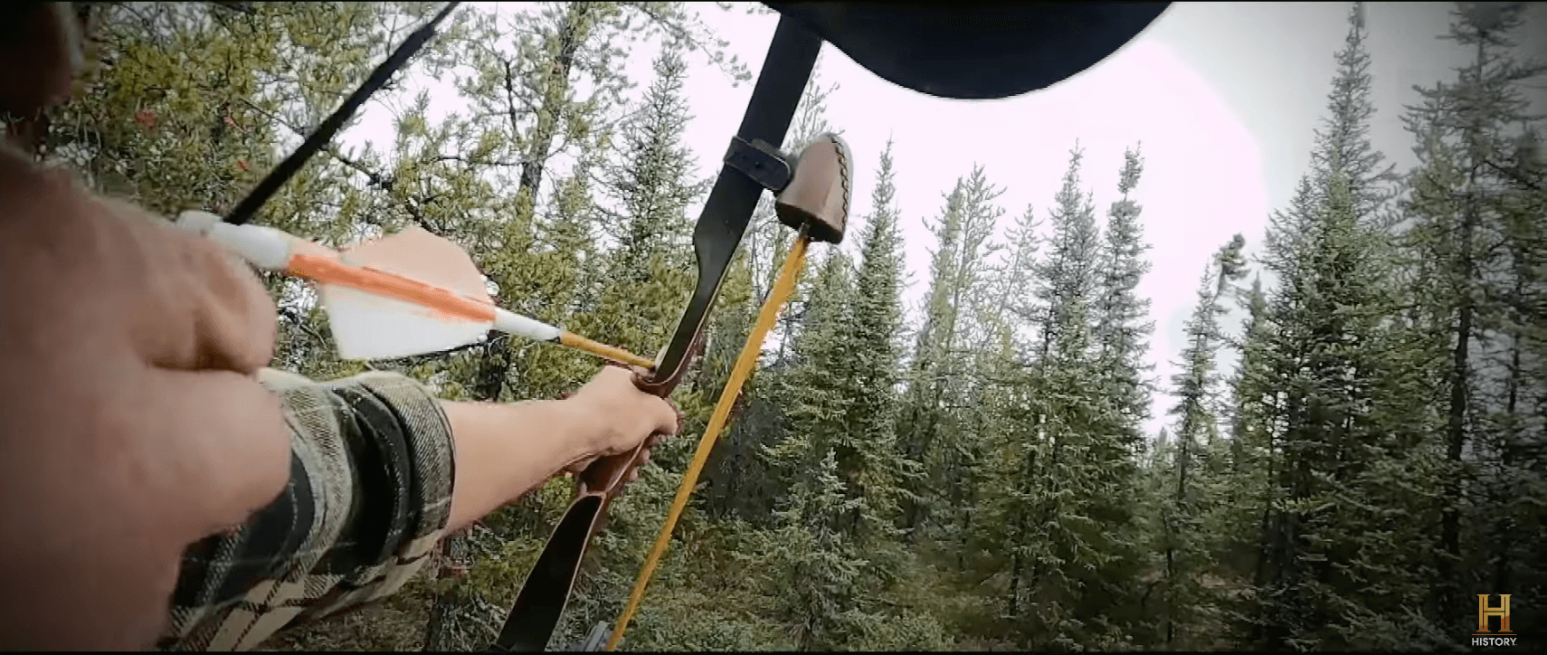 A competitor pulling back a bow and arrow, one of his specialty items, in 'Alone' Season 10