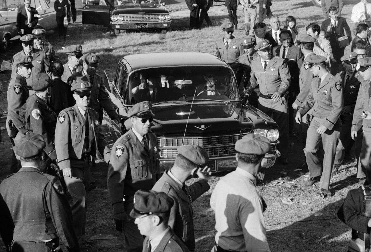 A black and white picture of police officers surrounding a car with The Beatles in it.