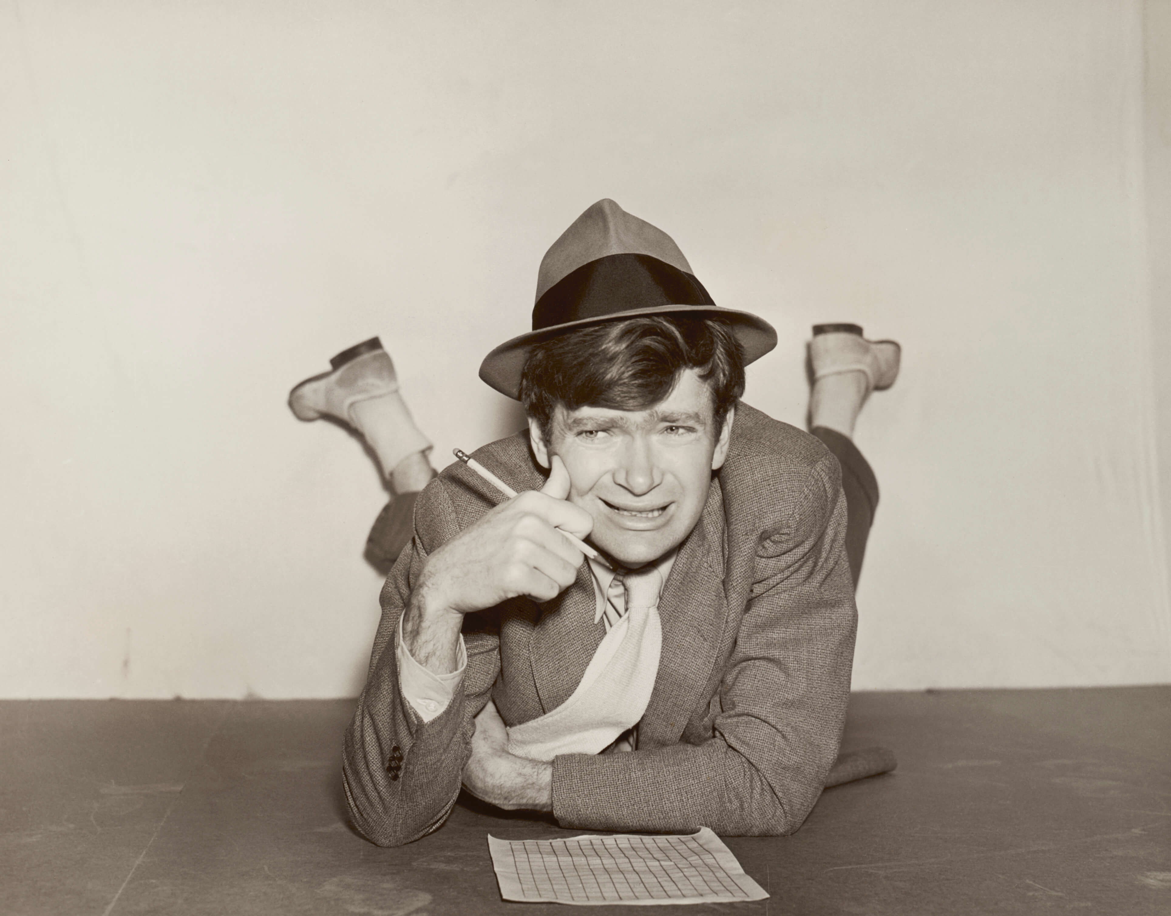 Buddy Ebsen lying down doing a crossword puzzle.