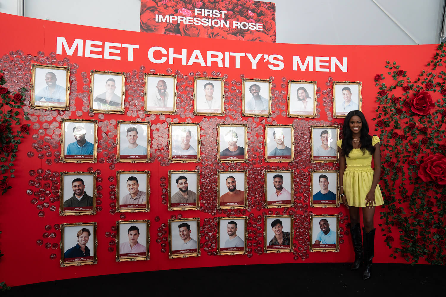 Charity Lawson from 'The Bachelorette' 2023 standing in front of a board showing the cast of her season. 
