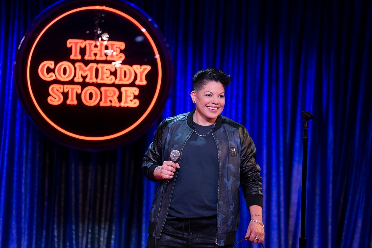 Sara Ramirez as Che Diaz stands in front of a 'The Comedy Store' sign in 'And Just Like That...' season 2