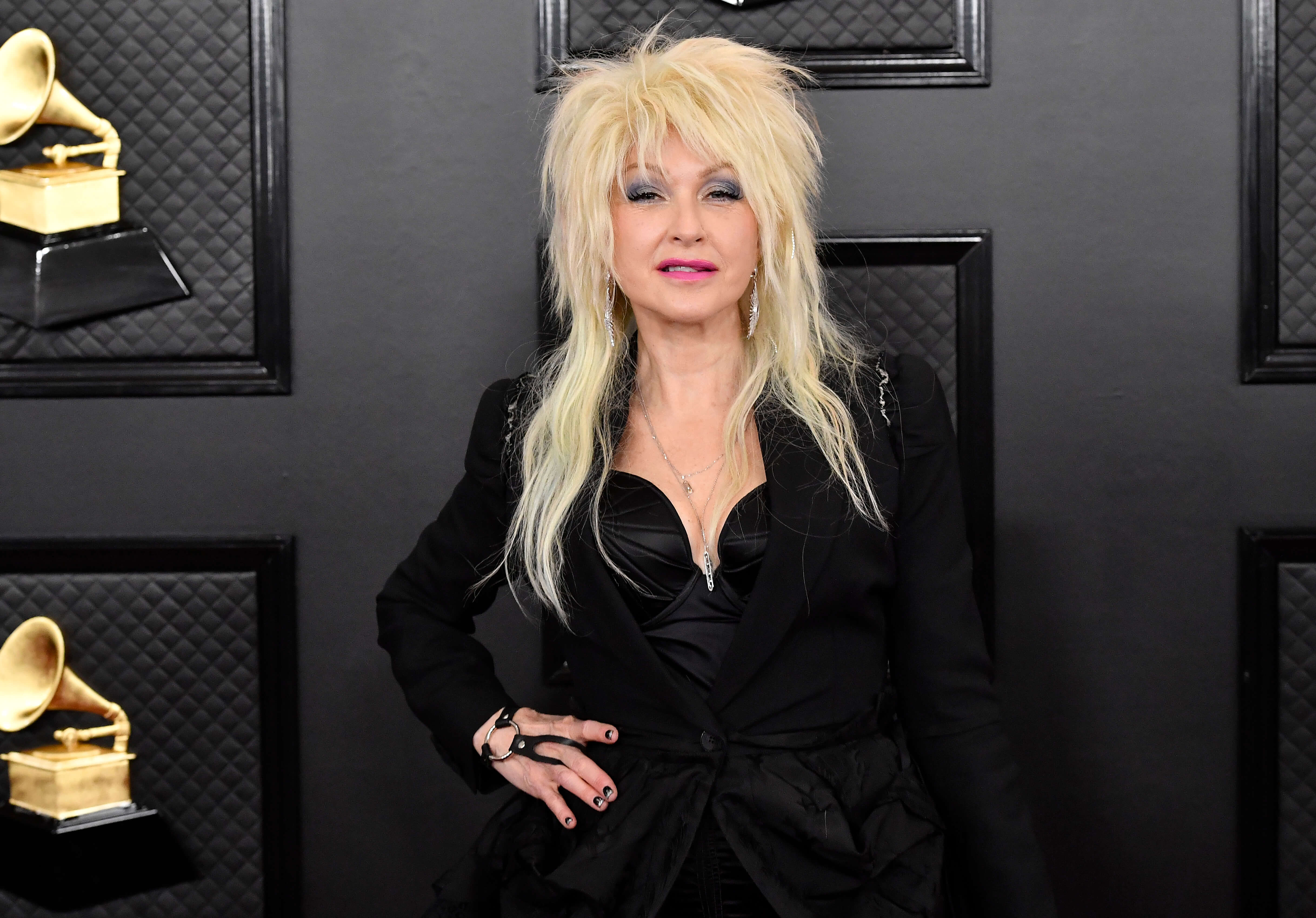Cyndi Lauper poses with blonde hair and a black outfit.