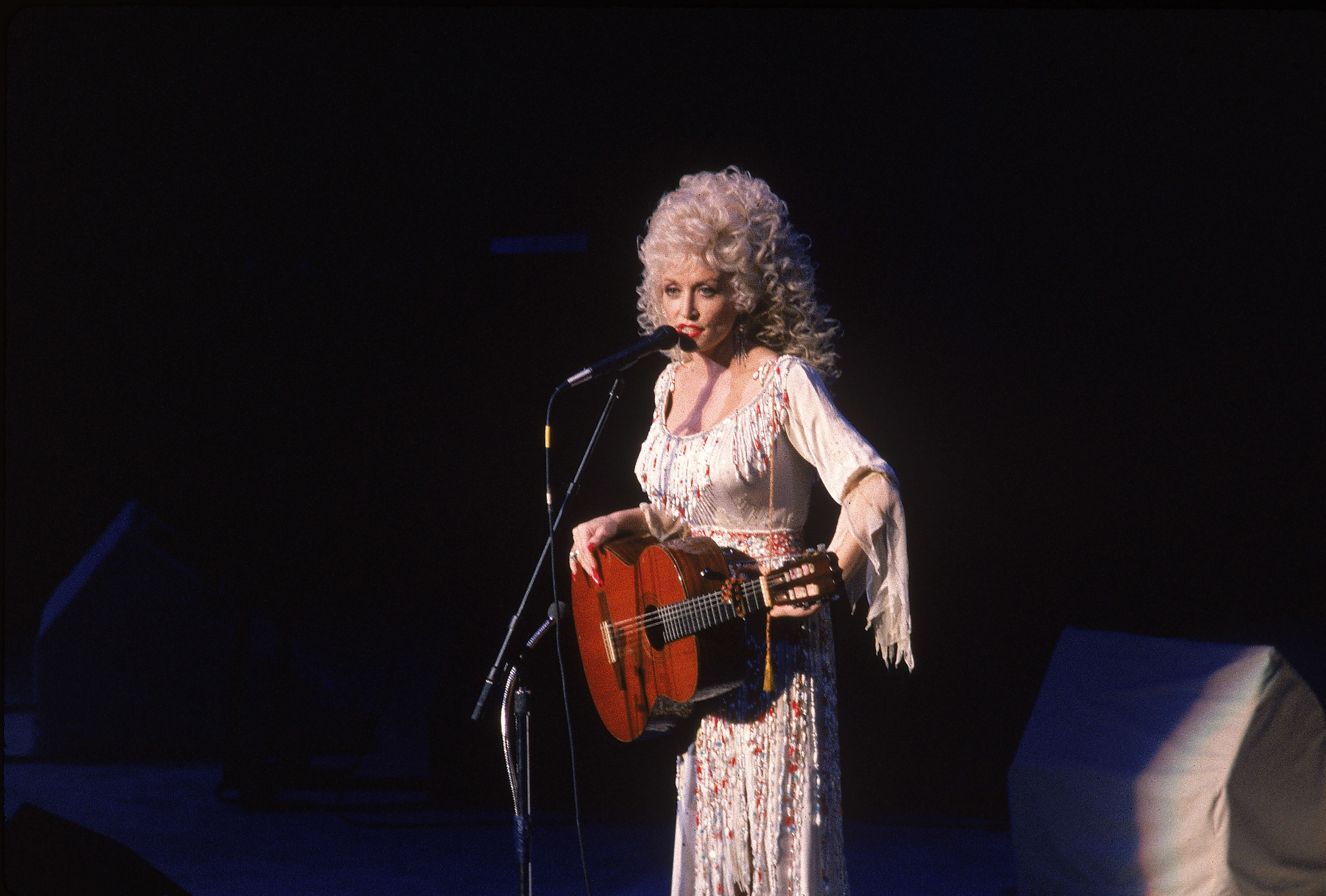 Dolly Parton on stage with a guitar. 