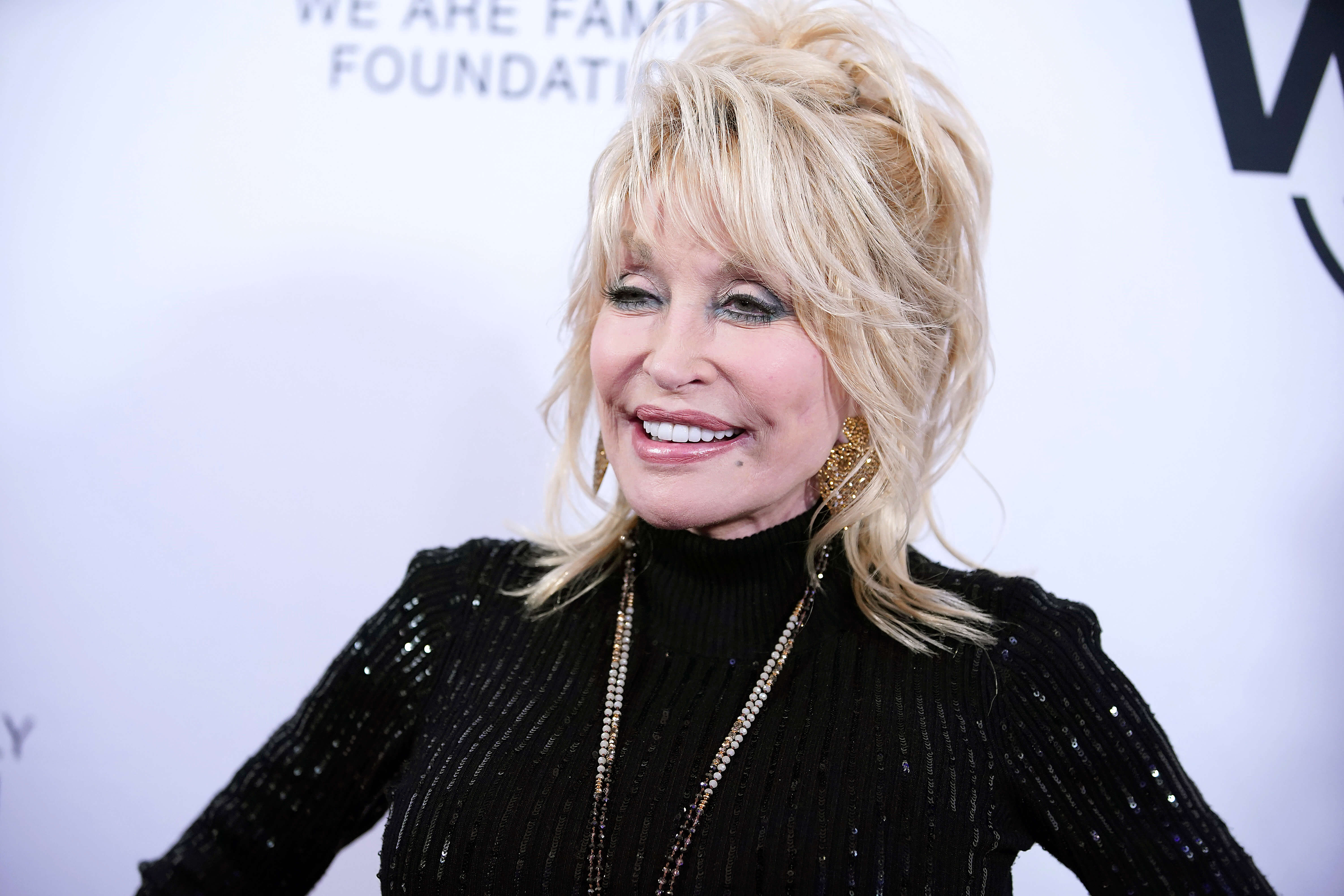 Dolly Parton smiling in a black turtleneck.