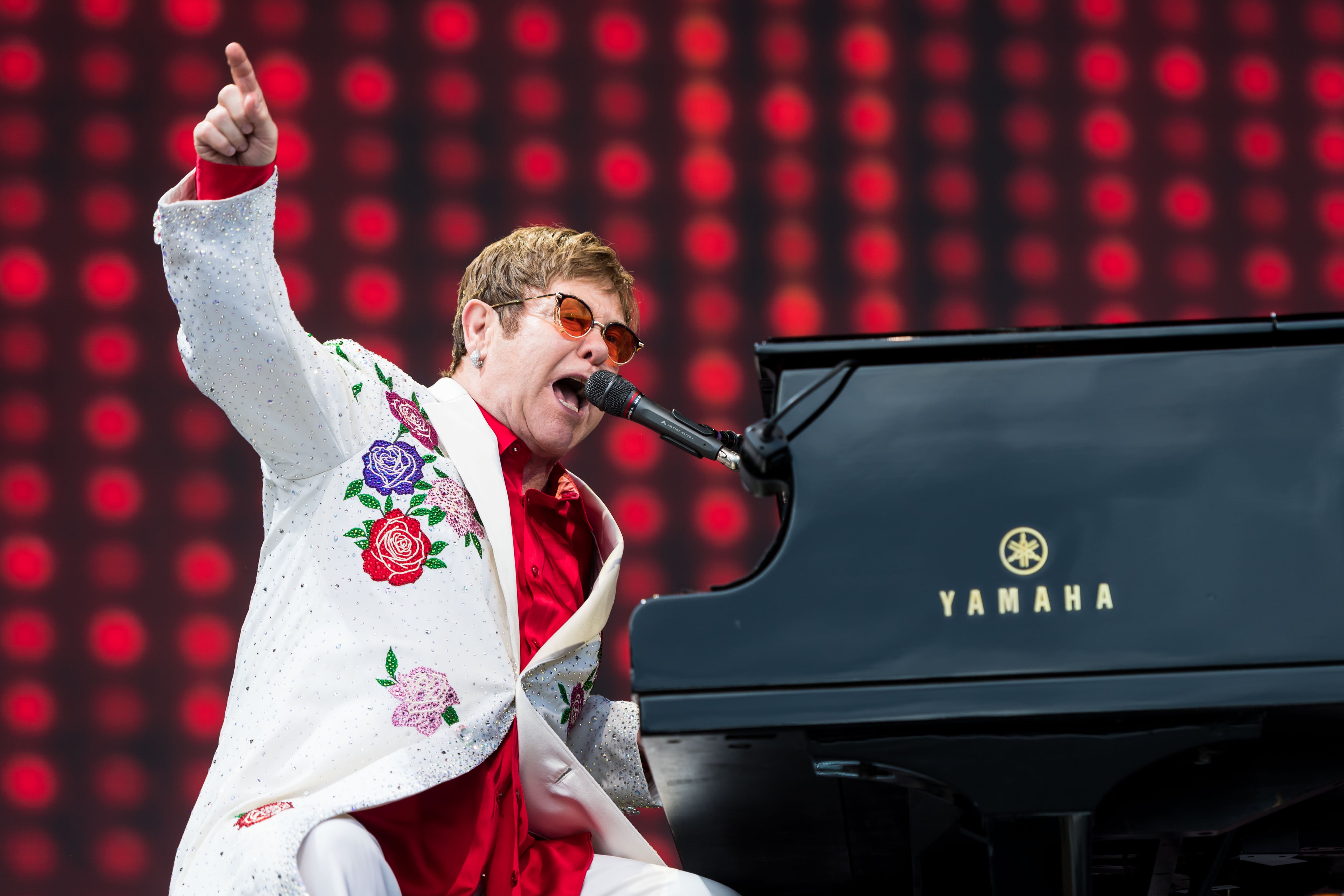 Elton John points while he plays the piano.