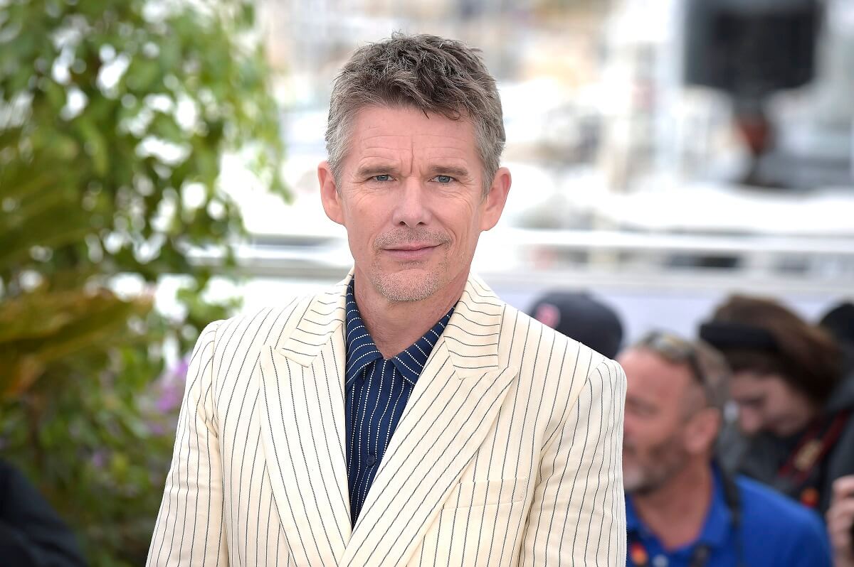 Ethan Hawke in a white suit taking a picture at the 2023 Cannes Film Festival.