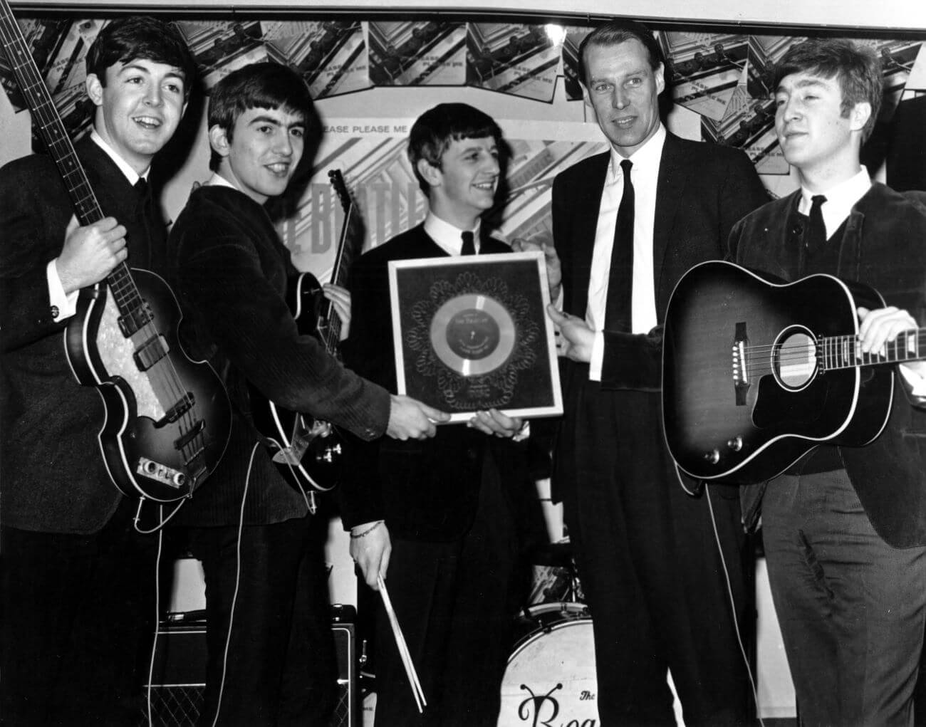 A black and white picture of Paul McCartney, George Harrison, Ringo Starr, George Martin, and John Lennon holding guitars and a record.