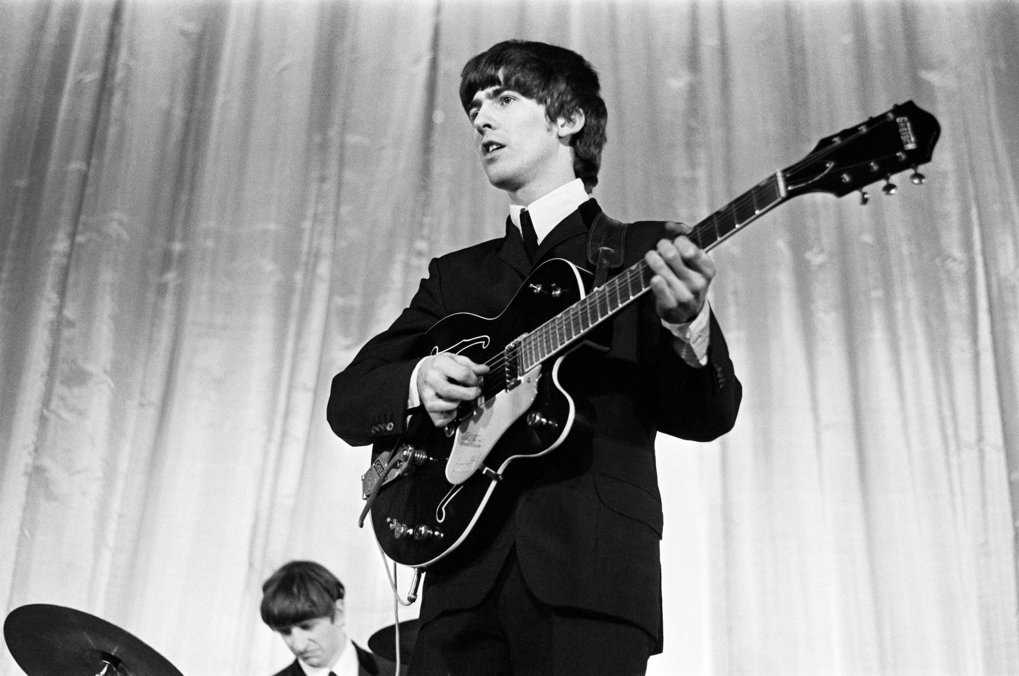 George Harrison plays guitar with The Beatles in 1964