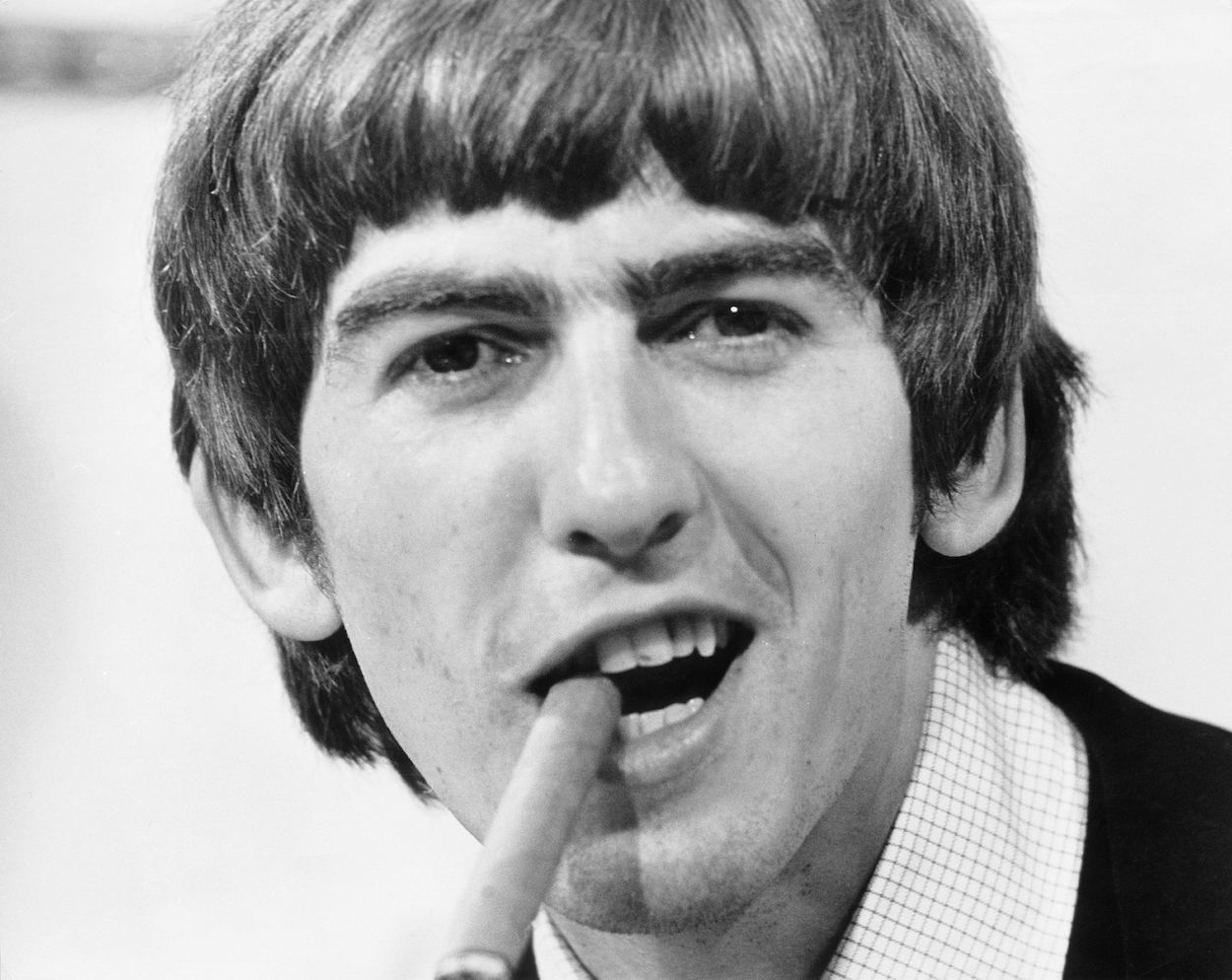 George Harrison chomping on a cigar and grinning on his 21st birthday in 1964.