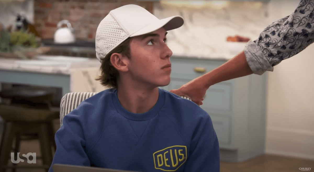 Grayson Chrisley of 'Chrisley Knows Best' wearing a white baseball hat and looking at someone