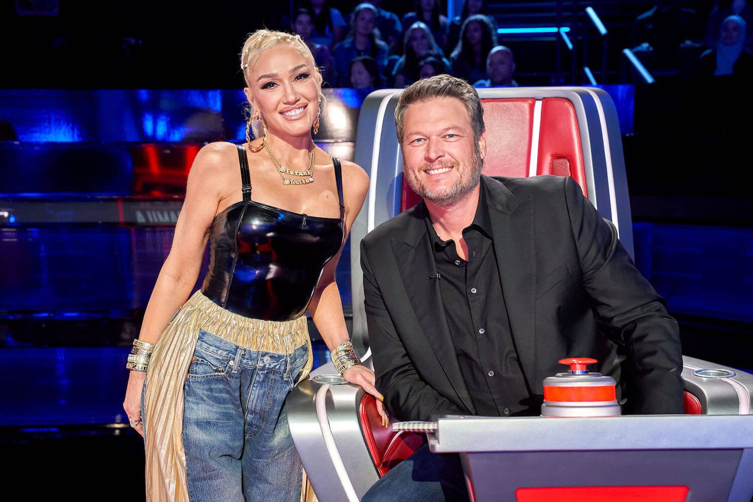 Gwen Stefani standing next to Blake Shelton while he sits in his chair on 'The Voice'