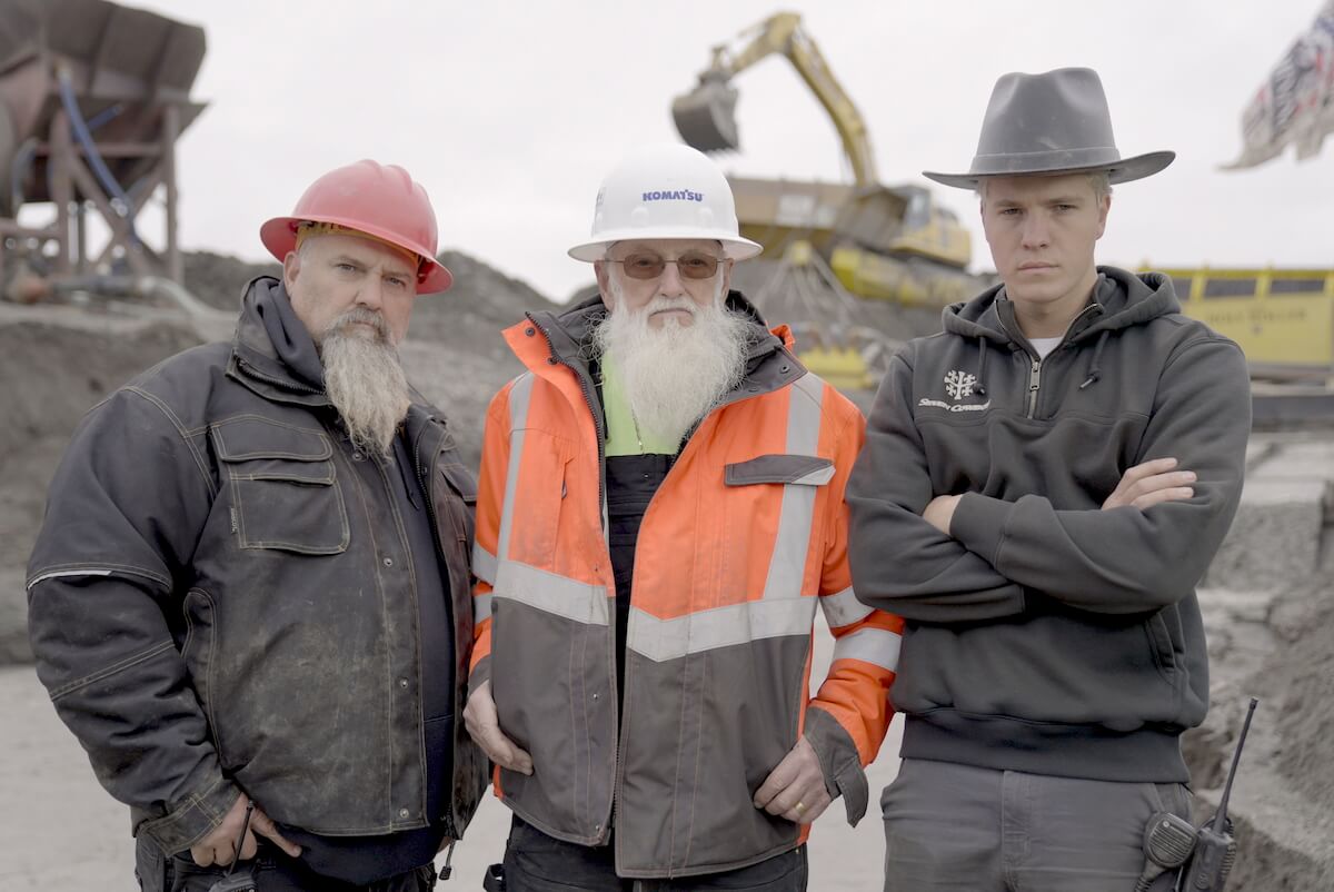 Todd Hoffman, Jack Hoffman, and Hunter Hoffman pose in front of mining equipment in promo shot for 'Hoffman Family Gold' Season 2
