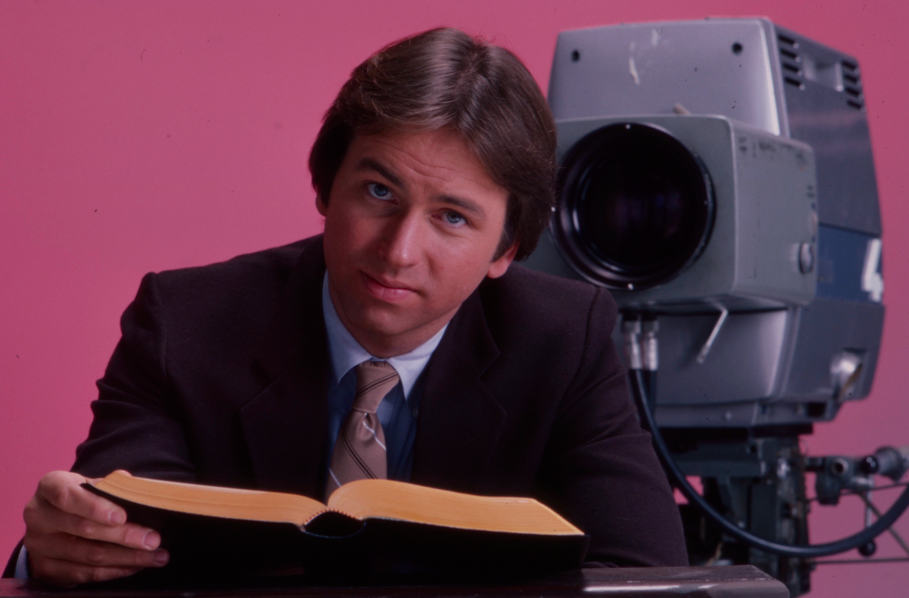 John Ritter poses in front of a camera.