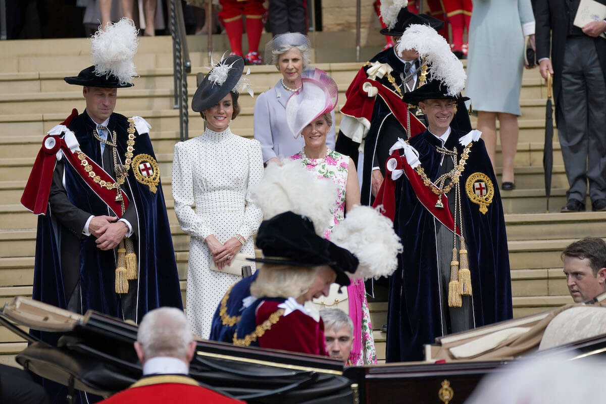 Kate Middleton and Sophie, Duchess of Edinburgh, who were likely laughing at their husbands 2023 Order of the Garter outfits, according to a body language expert, stand with Prince William and Prince Edward