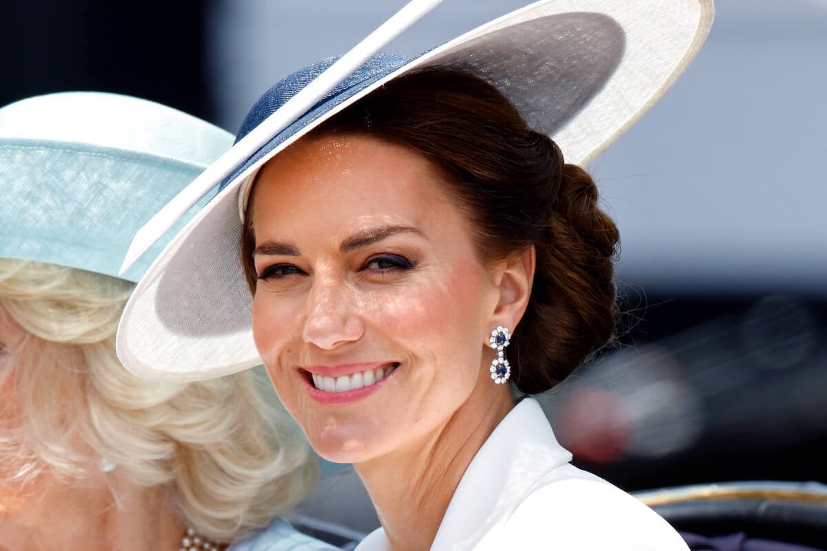 Kate Middleton, who may wear certain colors but avoid others with her 2023 Trooping the Colour outfit, smiles wearing a white outfit at Trooping the Colour in 2022