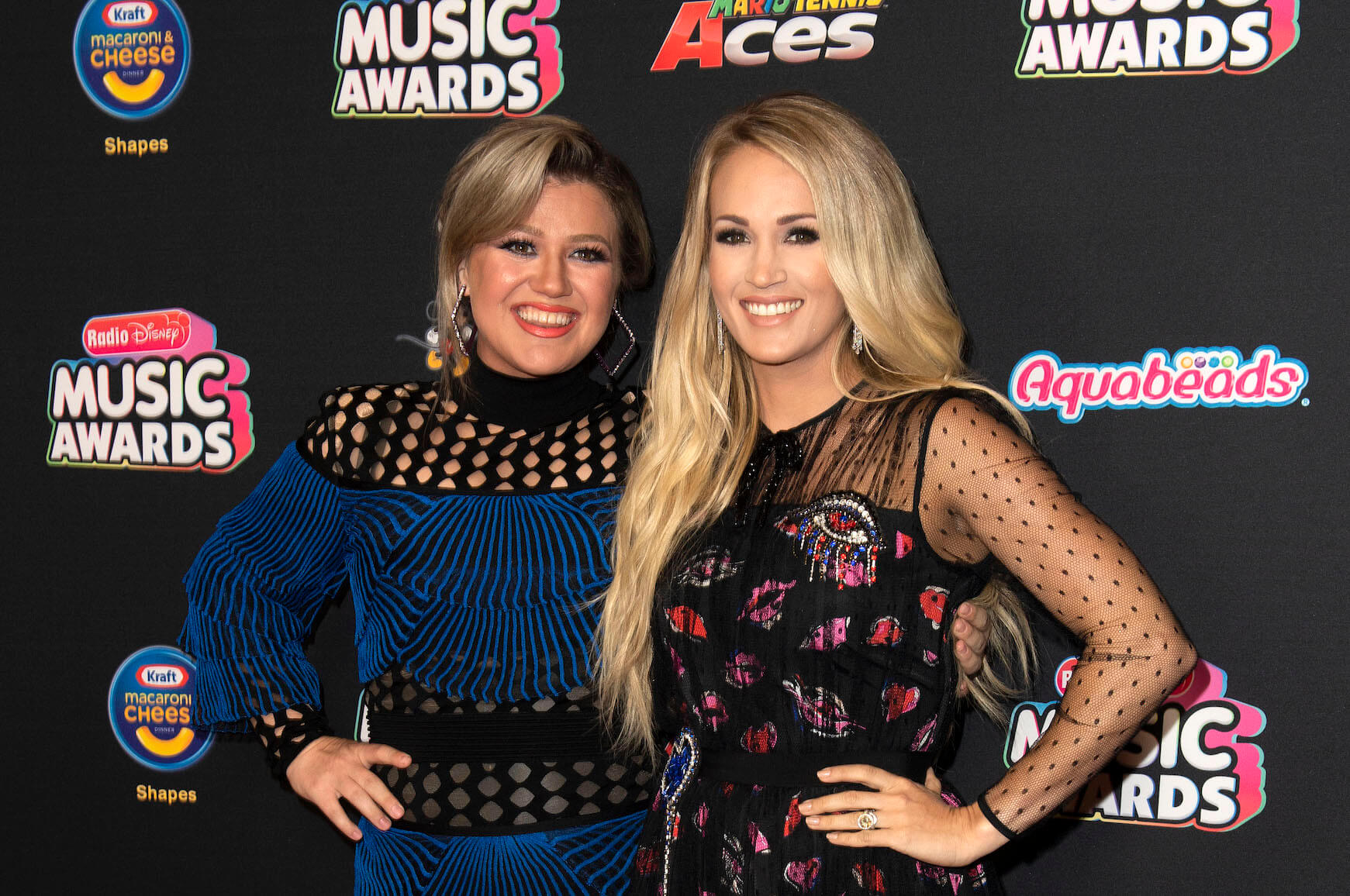 'The Voice' coach Kelly Clarkson and 'American Idol' alumnus Carrie Underwood standing together and hugging