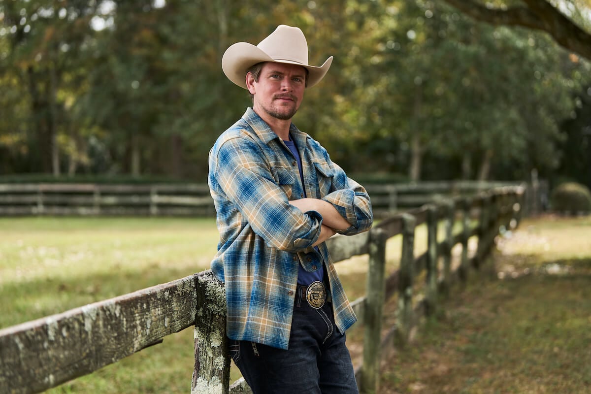 Landon from 'Farmer Wants a Wife' leaning on a fence and wearing a cowboy hat