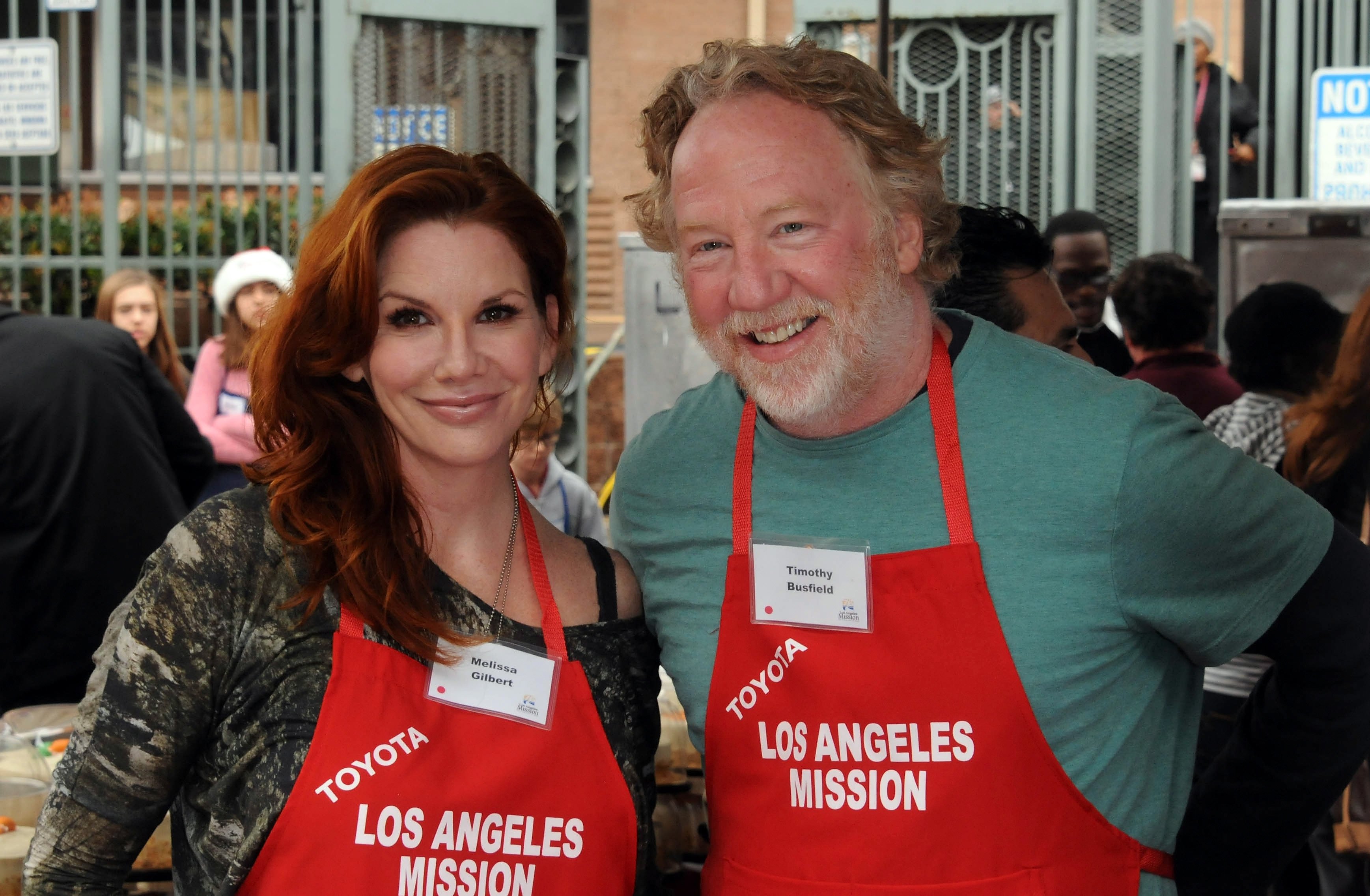 Melissa Gilbert and Timothy Busfield in red aprons.