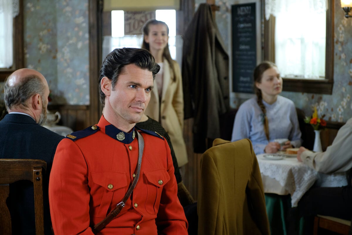 Kevin McGarry as Nathan in a red mountie uniform sitting at a table in 'When Calls the Heart'