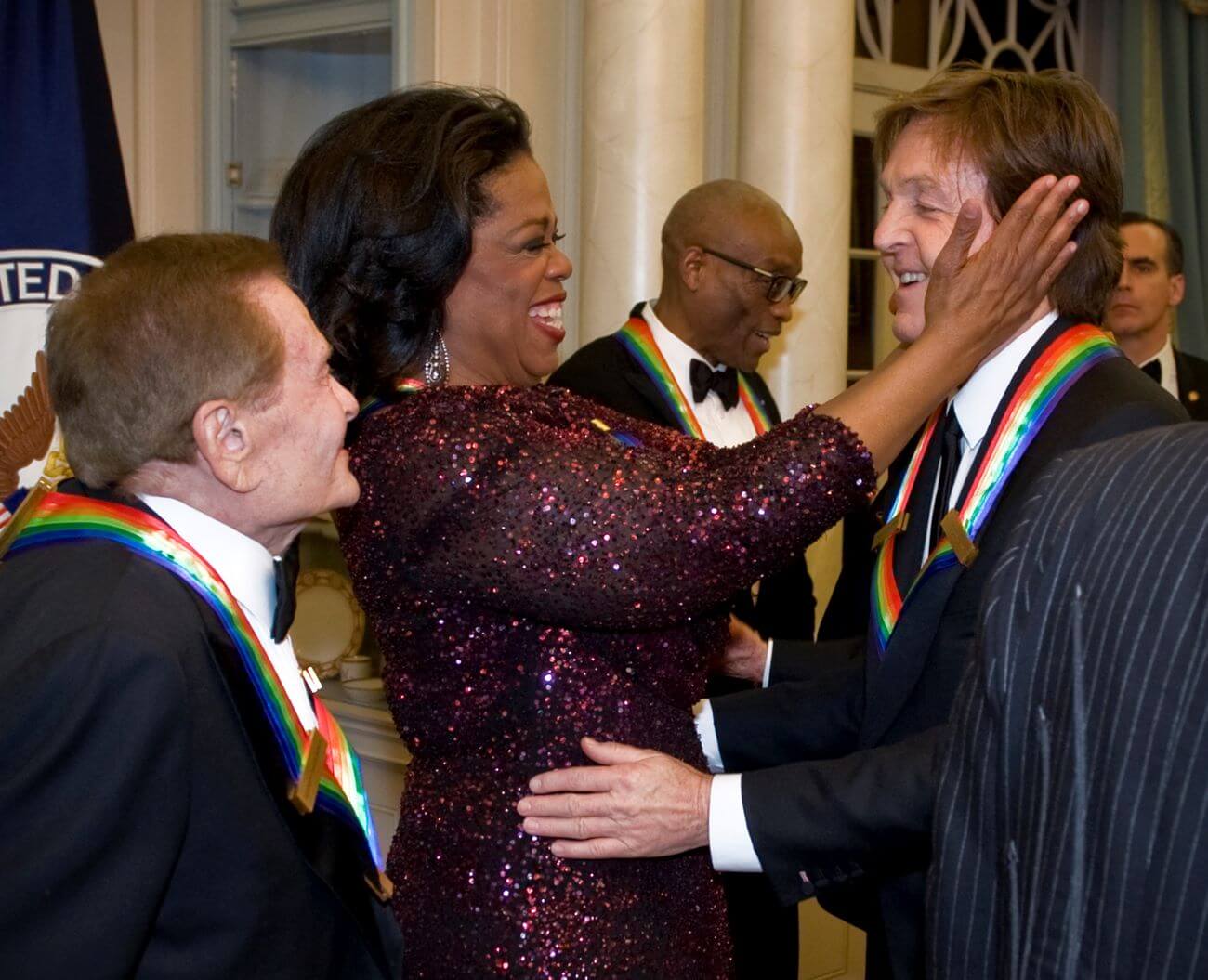 Oprah grasps Paul McCartney's face at the Kennedy Center Honors while fellow honoree Jerry Herman looks on. Bill T. Jones stands behind them.