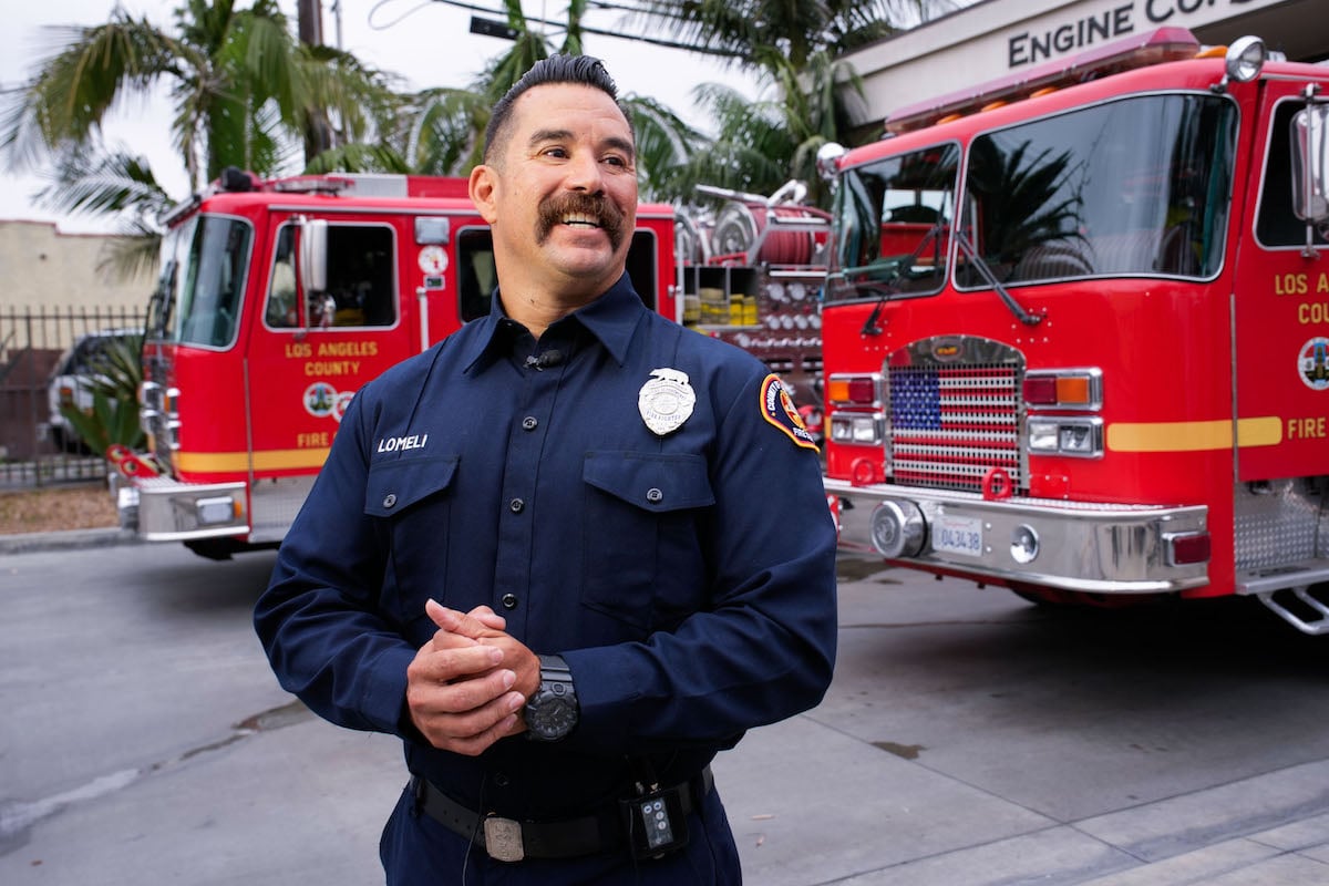 A firefighter from 'LA Fire & Rescue' standing in front of fire trucks