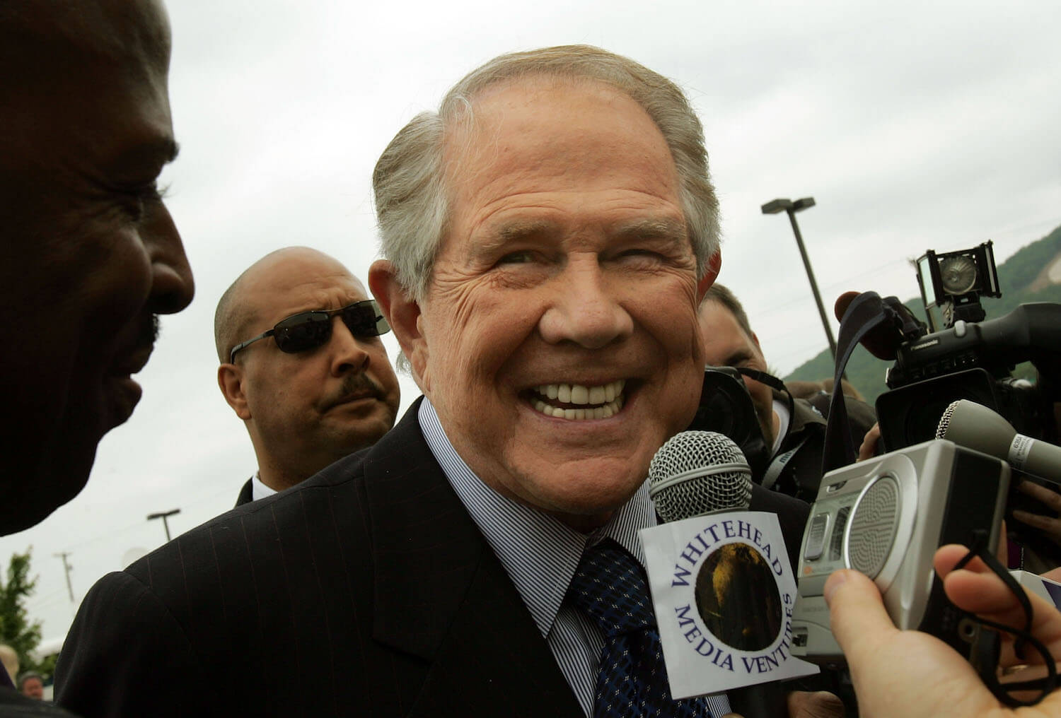 Christian Broadcasting Network founder Pat Robertson smiling around reporters