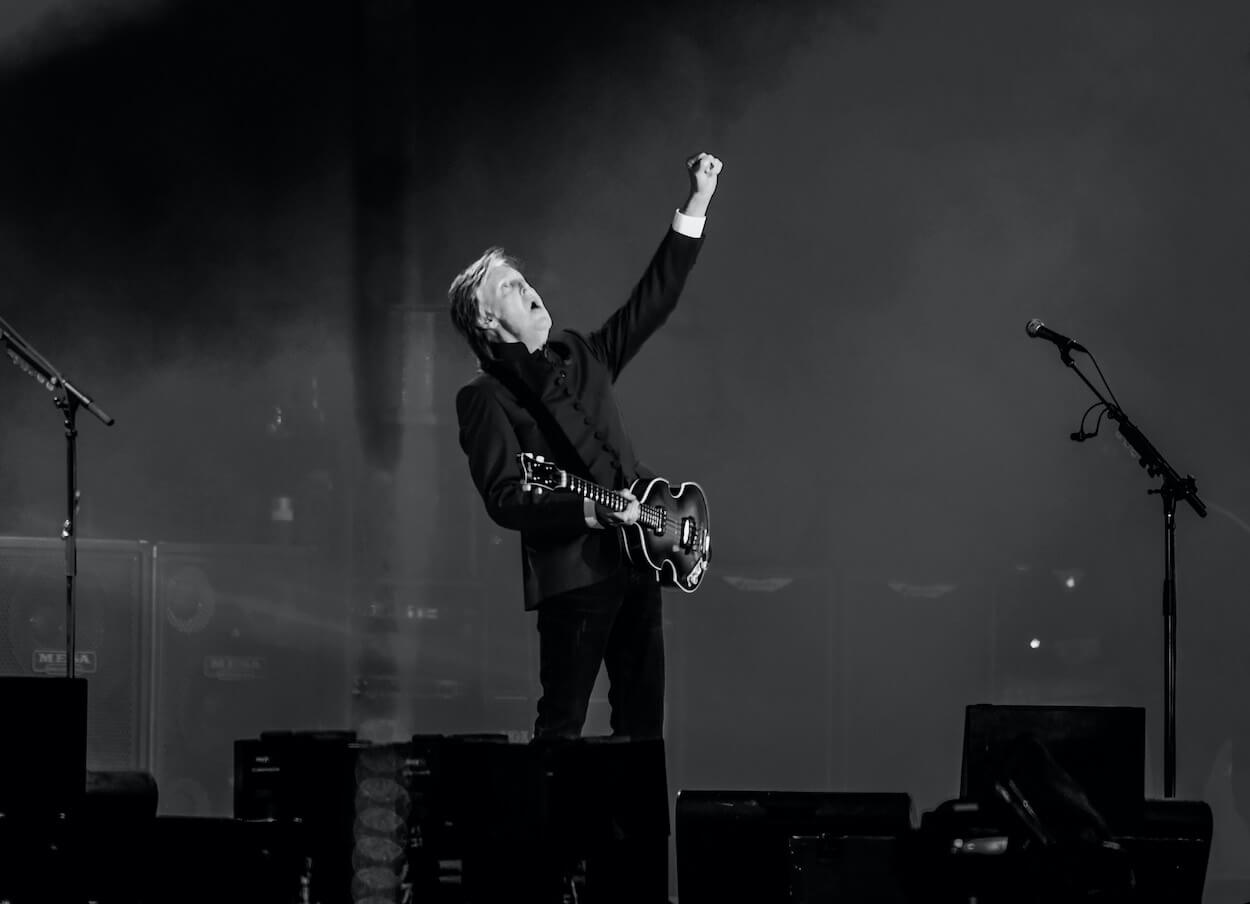 Paul McCartney lifts his left hand into the air while playing bass at the 2022 Glastonbury festival.