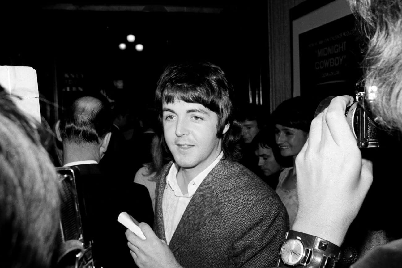A black and white picture of Paul McCartney walking through a crowd.