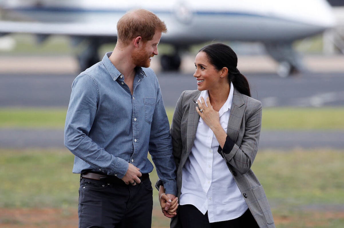 Prince Harry and Meghan Markle, whose daughter Princess Lilibet didn't get a royal family birthday shoutout, look at each other