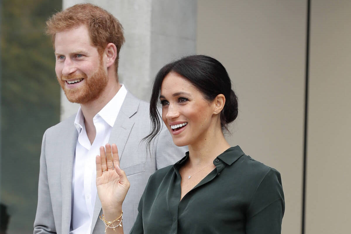 Prince Harry and Meghan Markle, whose wardrobes often have the 'common theme' of green, smile