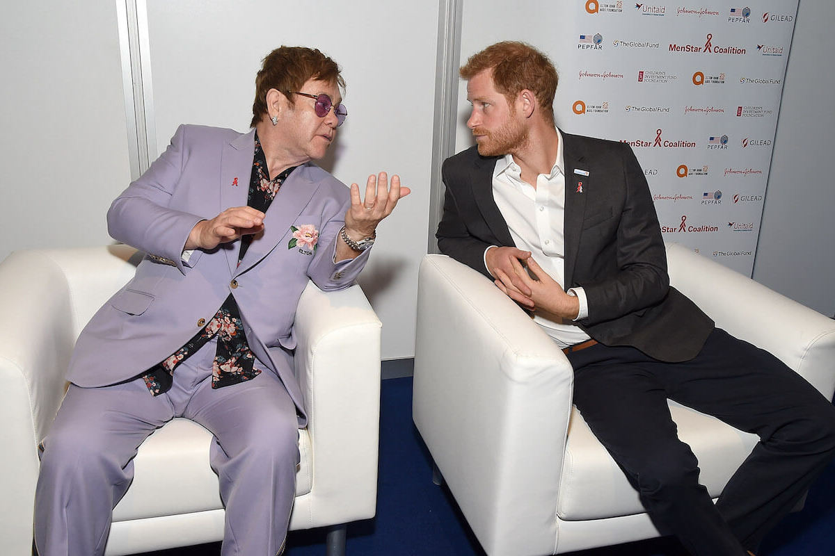 Prince Harry, whose phone hacking lawsuit has a connection to Elton John, sits with Elton John