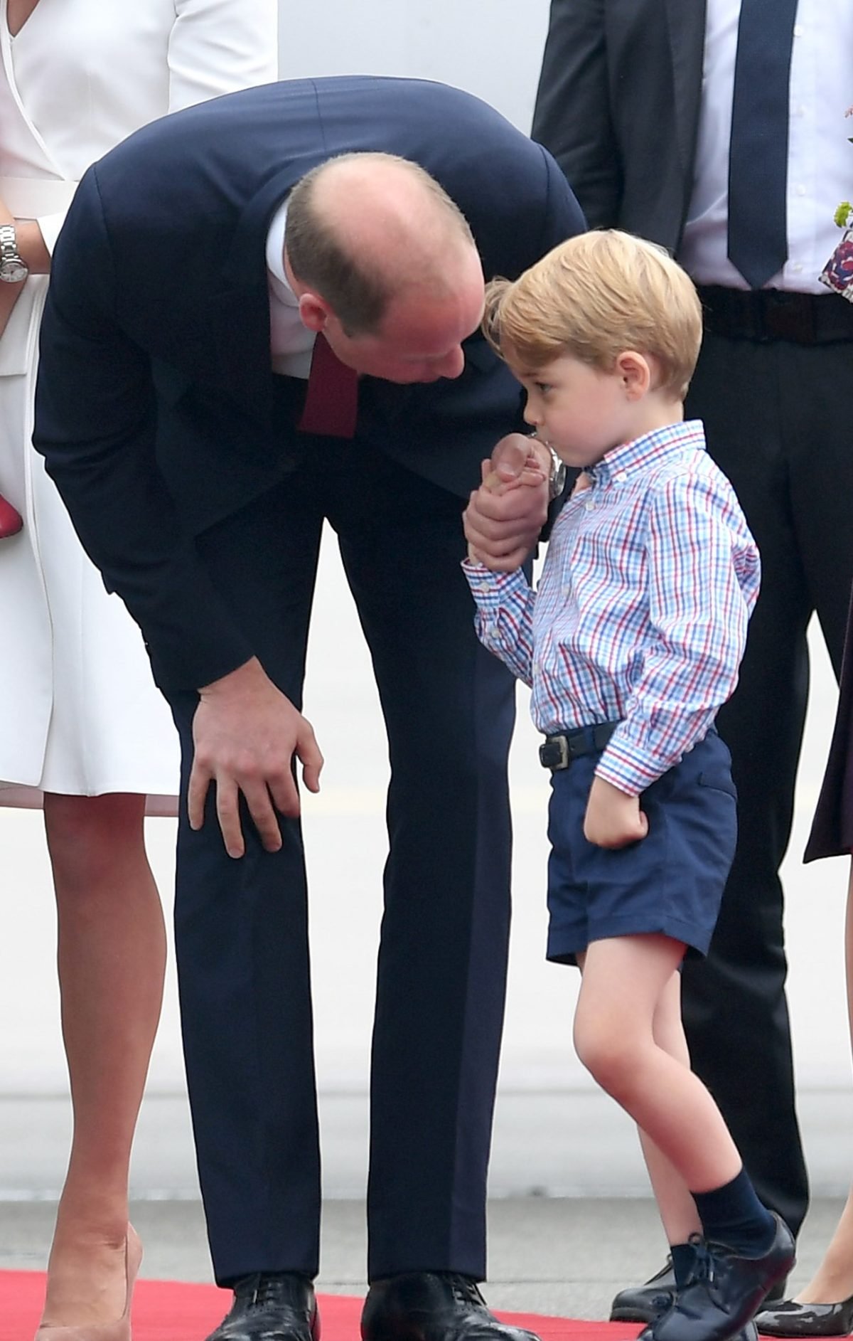 Prince William bending down to talk to his son Prince George when they arrive at Warsaw airport for Royal Tour of Poland and Germany