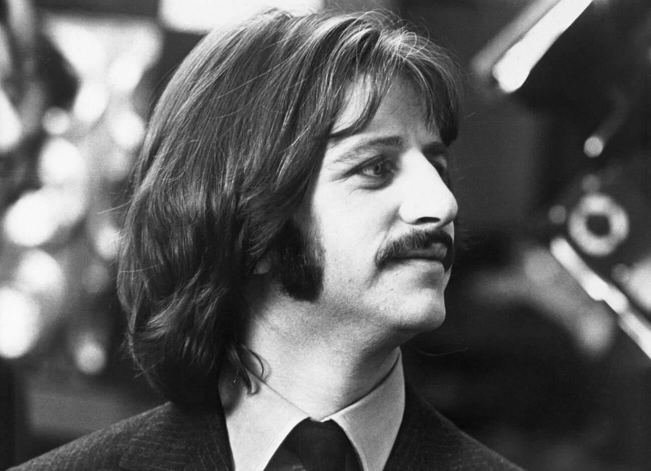 A black and white picture of Ringo Starr wearing a suit and looking to his left.