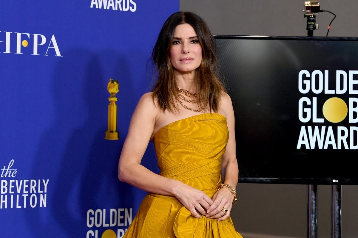 Sandra Bullock posing in a yellow dress at the Golden Globe Awards.