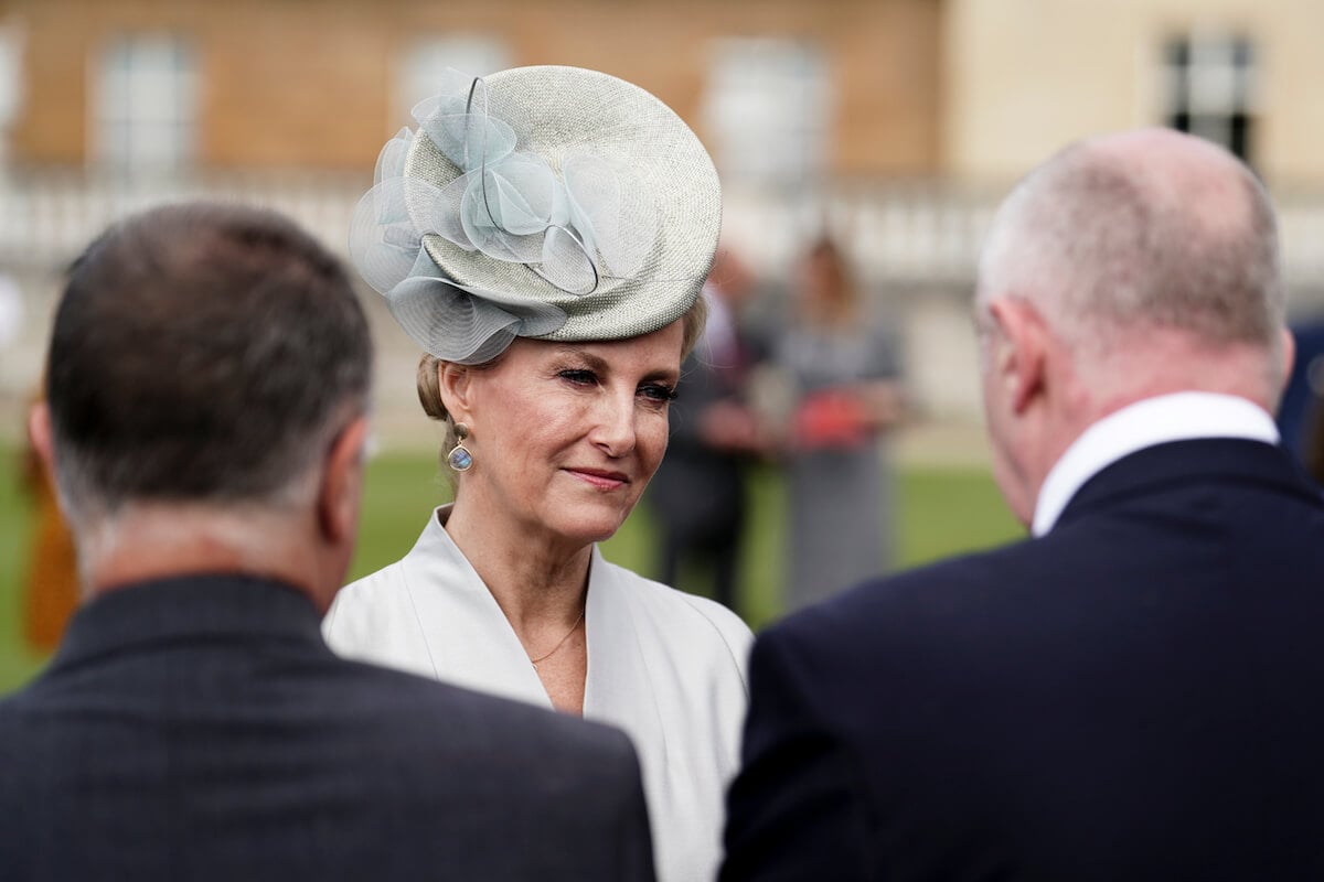Sophie, Duchess of Edinburgh, who said in 2021 menopause has made her lose her train of thought during royal engagements, talks to two men at a garden party