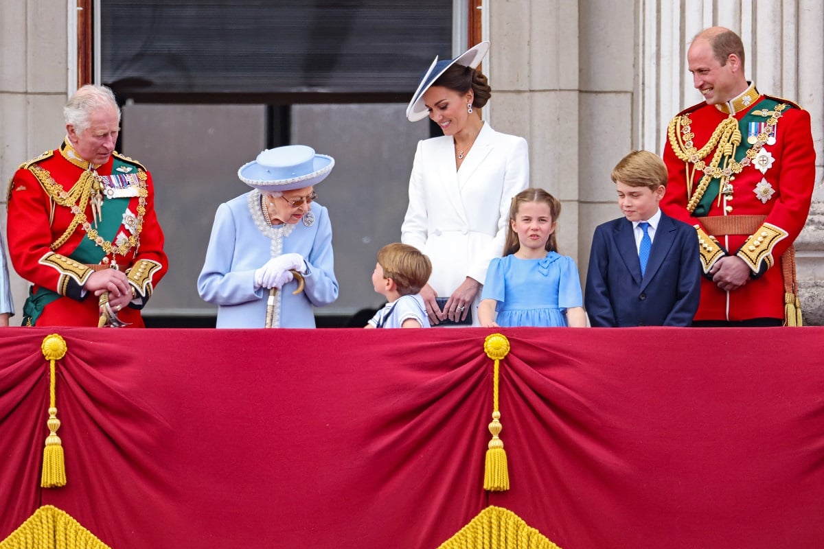 Then-Prince Charles and Queen Elizabeth II standing on the Buckingham Palace balcony with Charles' favorite grandchild and the queen's favorite great-grandchild