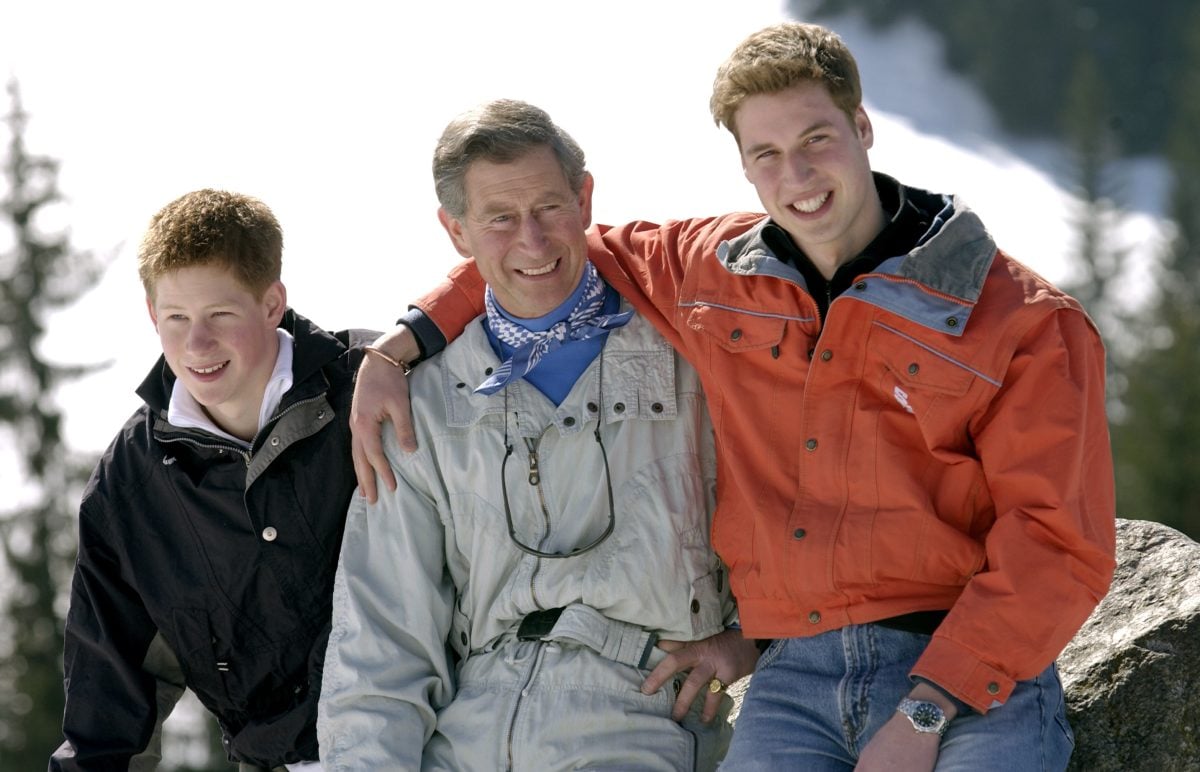 Then-Prince Charles smiling with Prince William and Prince Harry during a family ski trip