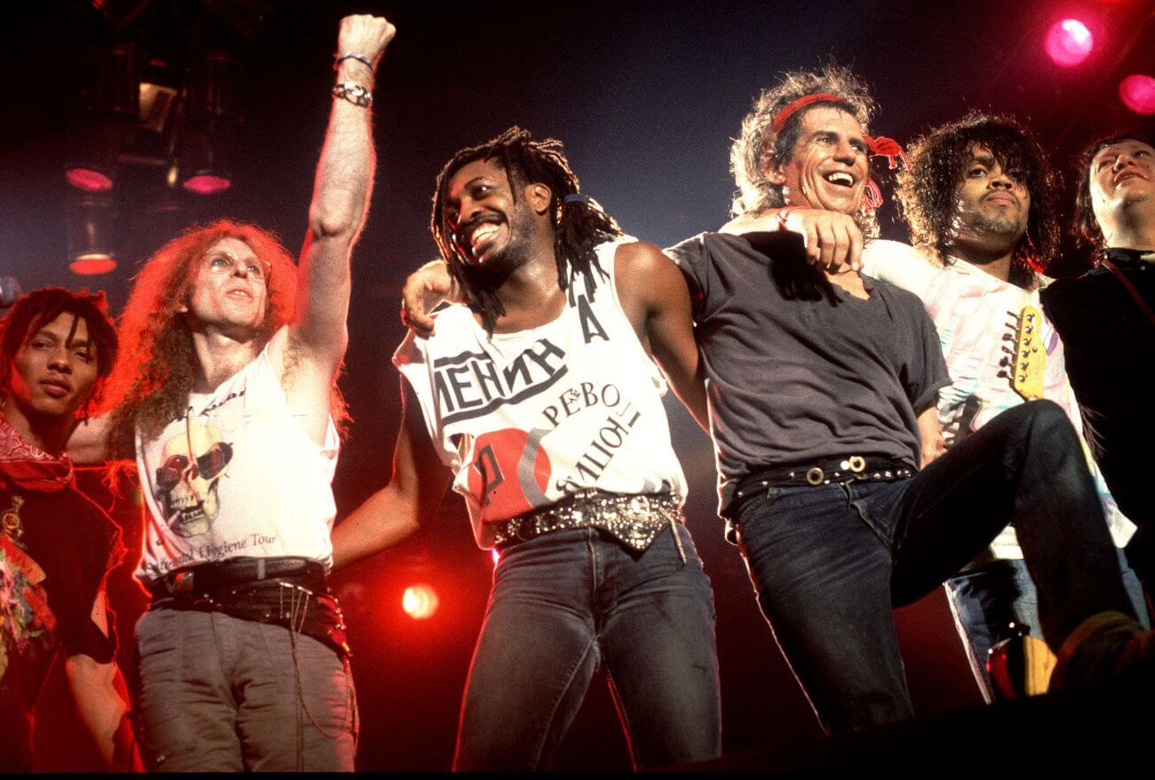 Ivan Neville, Waddy Wachtel, Steve Jordan, Keith Richards, Charlie Drayton and Bobby Keys of the X-Pensive Winos stand arm in arm on stage.